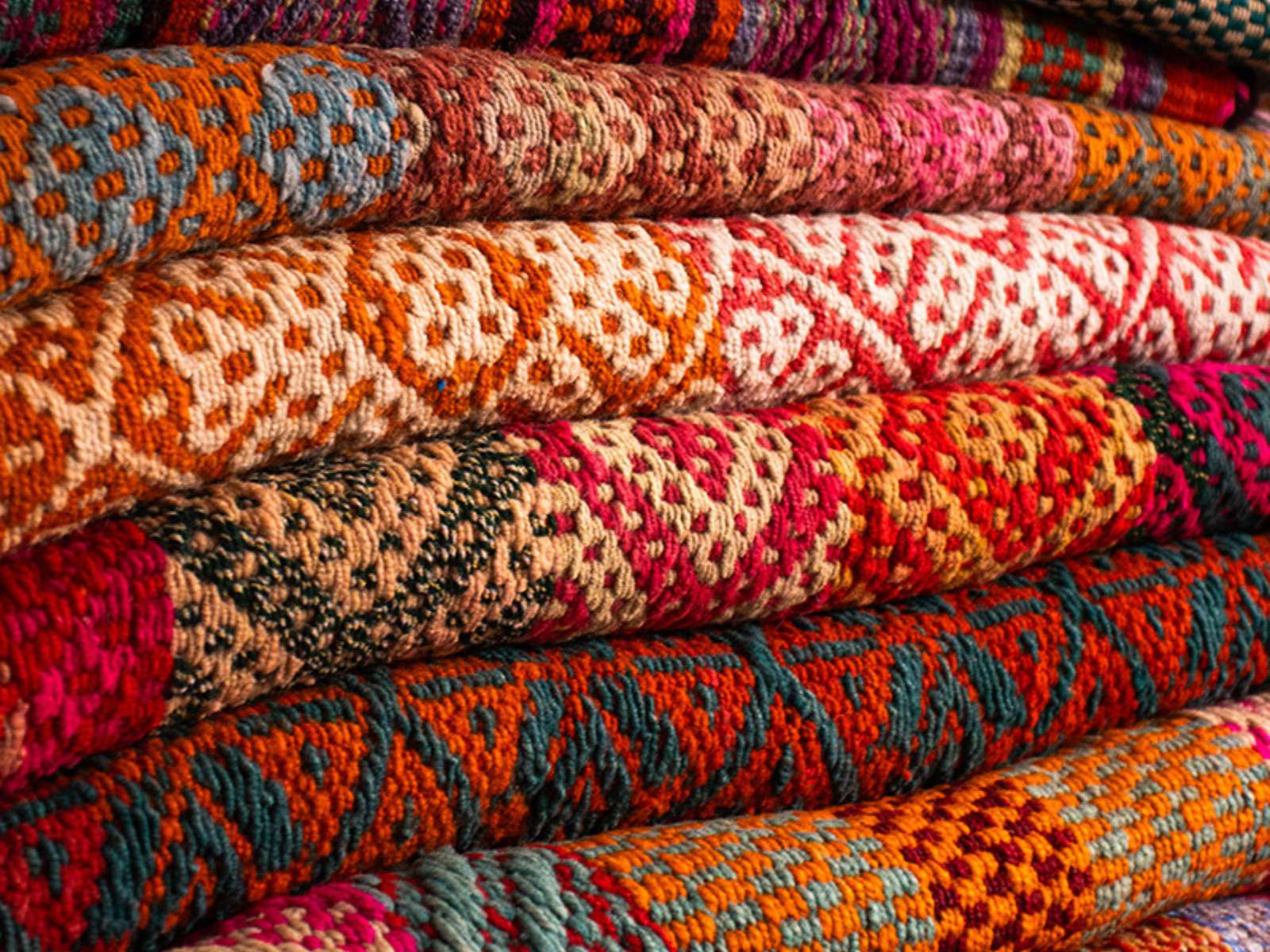 Stack of handwoven Peruvian frazadas in vibrant natural dyes — vintage wool textiles from the Andean highlands | Orange Inca