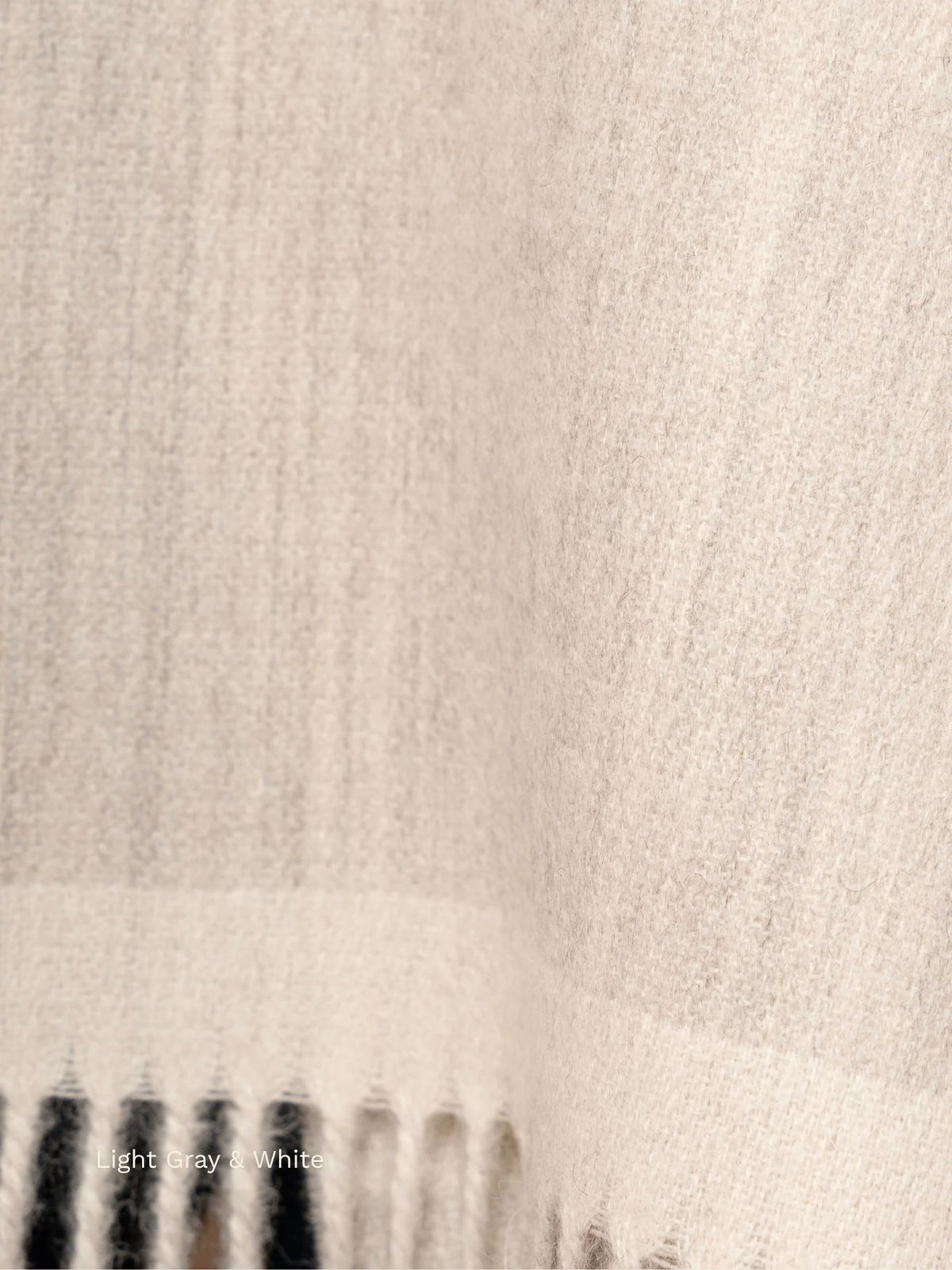 Light grey and white double face baby alpaca scarf, close-up of the soft two-sided fabric and fringe
