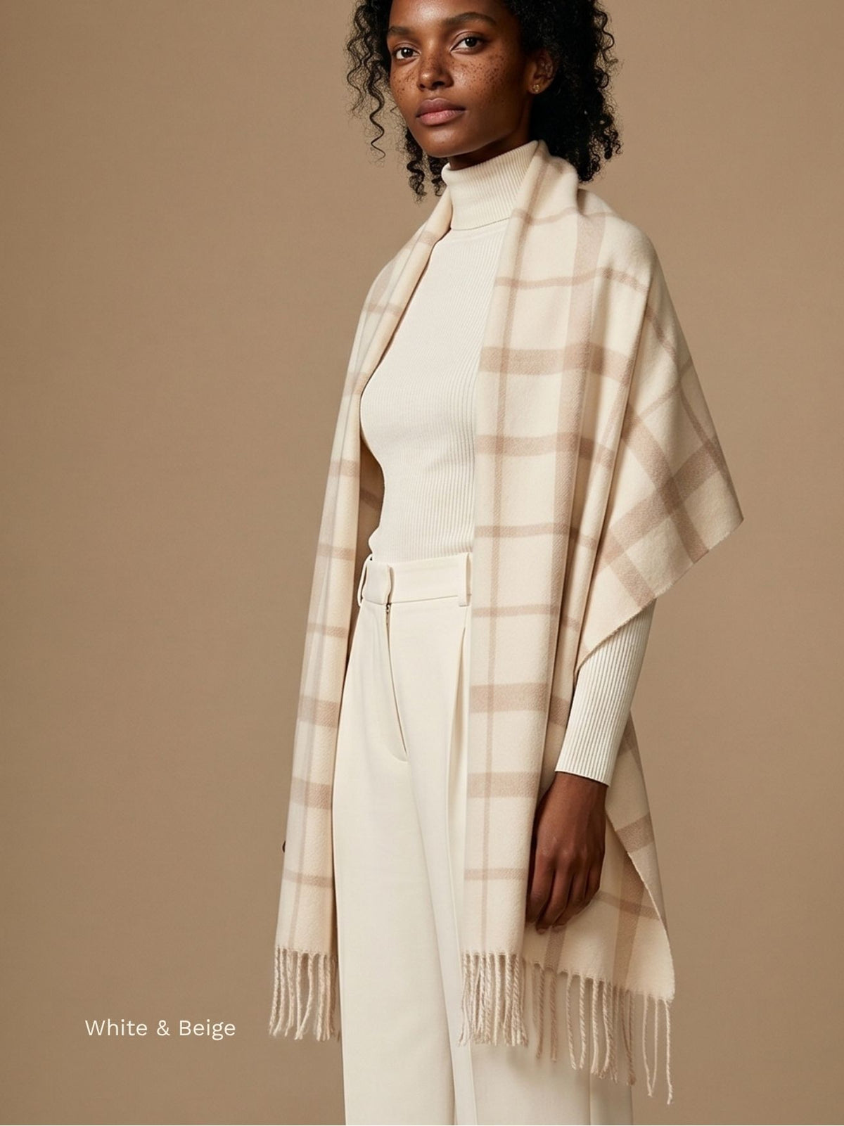 Woman wearing a white and beige plaid baby alpaca scarf draped as a wrap over a cream turtleneck and trousers. Orange Inca