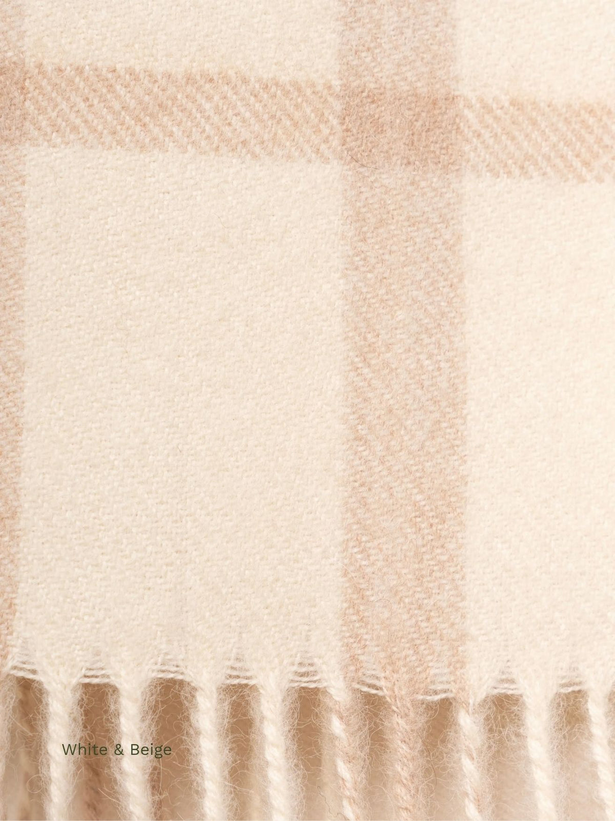 Close-up of the beige check pattern and fringe on a white and beige plaid baby alpaca scarf