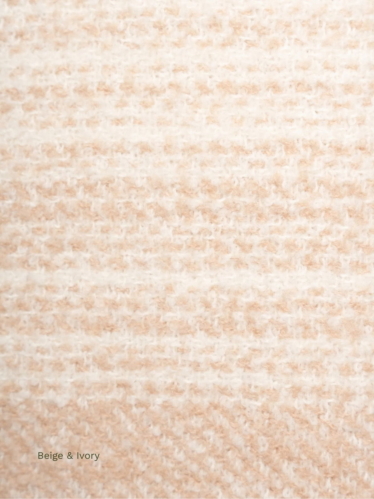 Close-up of the beige and ivory striped bouclé texture of a baby alpaca scarf