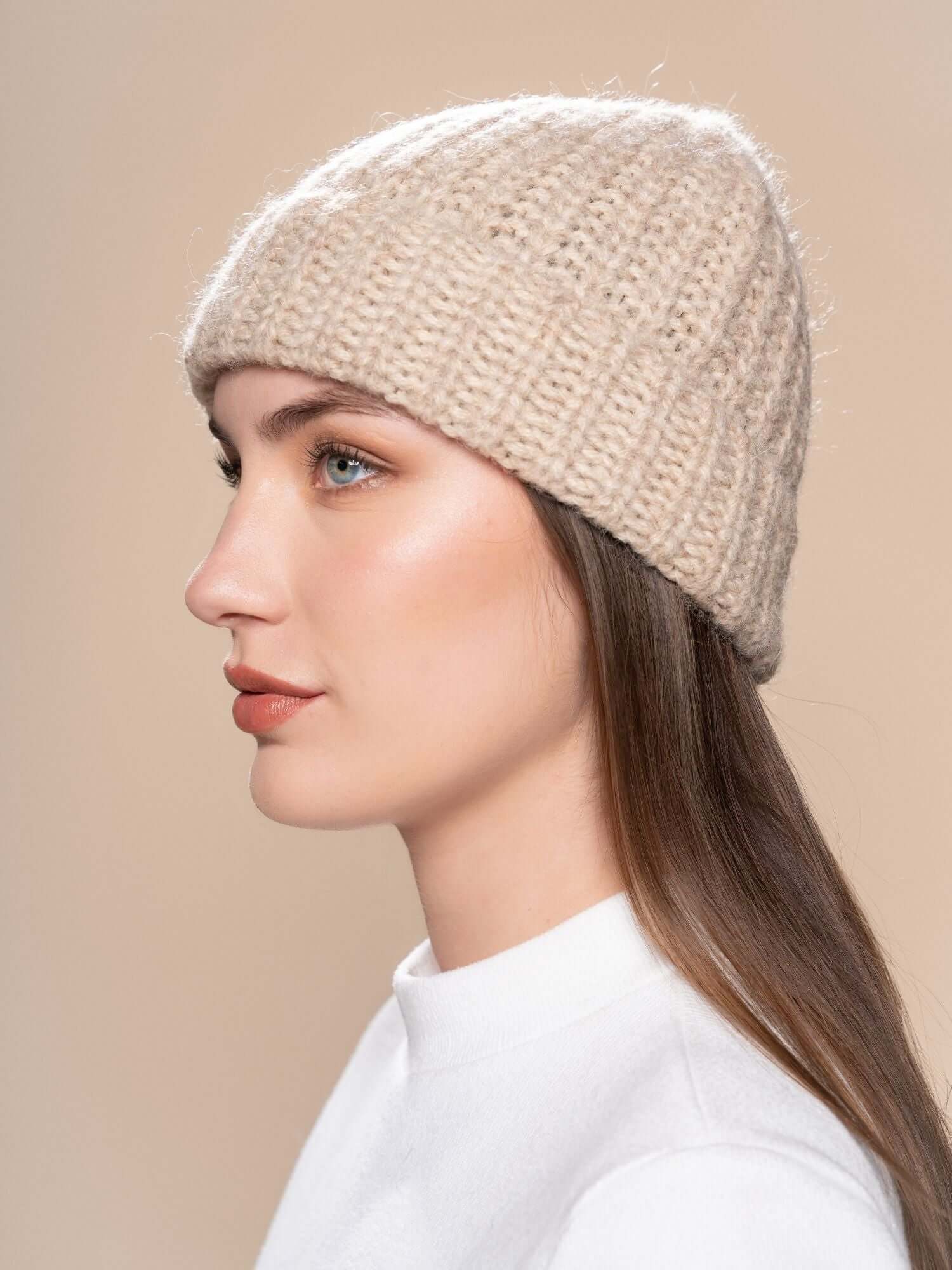Side view of beige baby alpaca chunky knit beanie on model