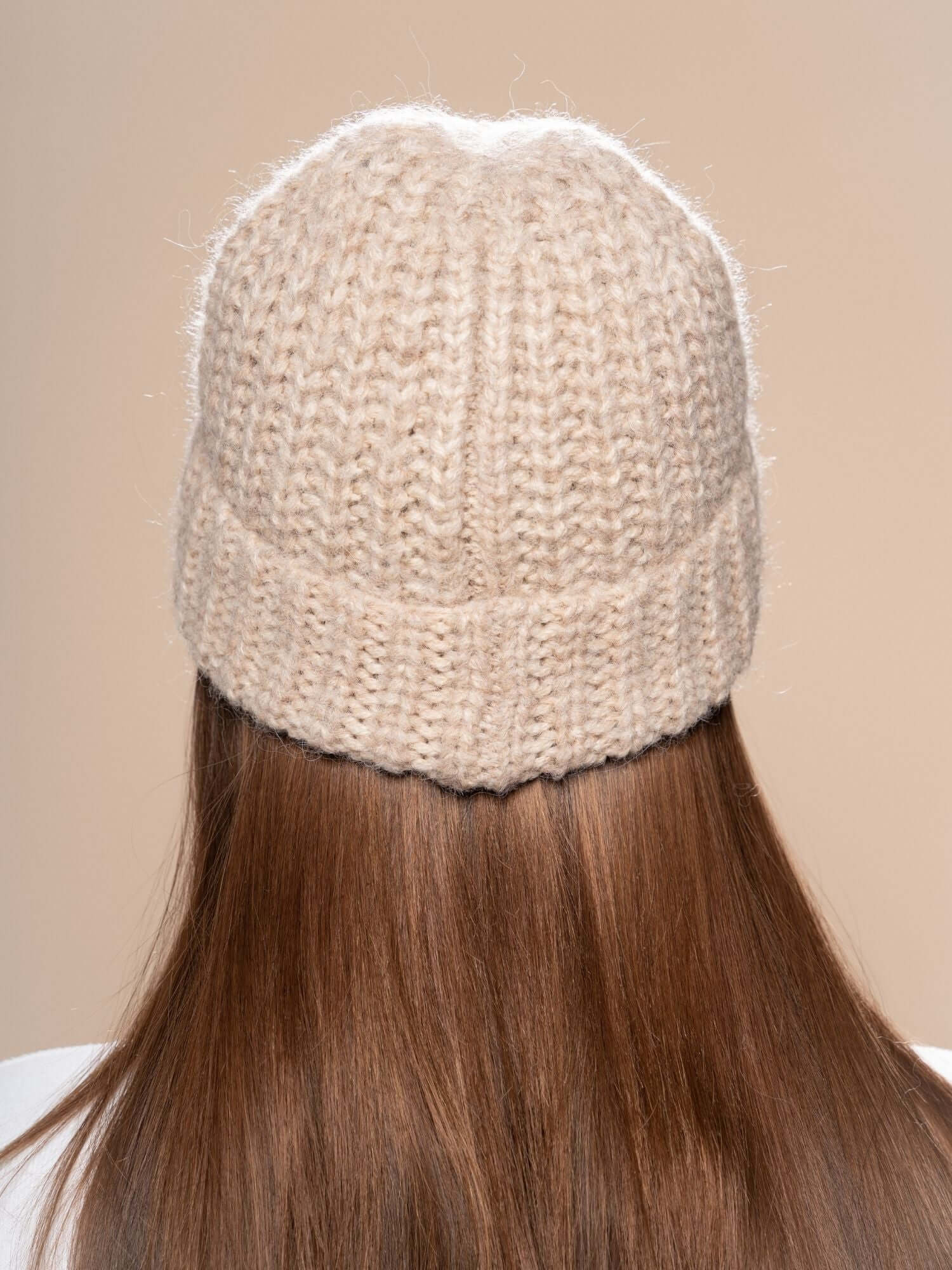 Back view of beige chunky knit beanie on long brown hair