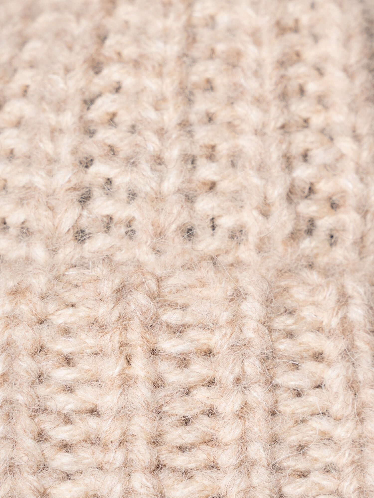 Flat-lay of beige beanie hat showing thick alpaca knit texture