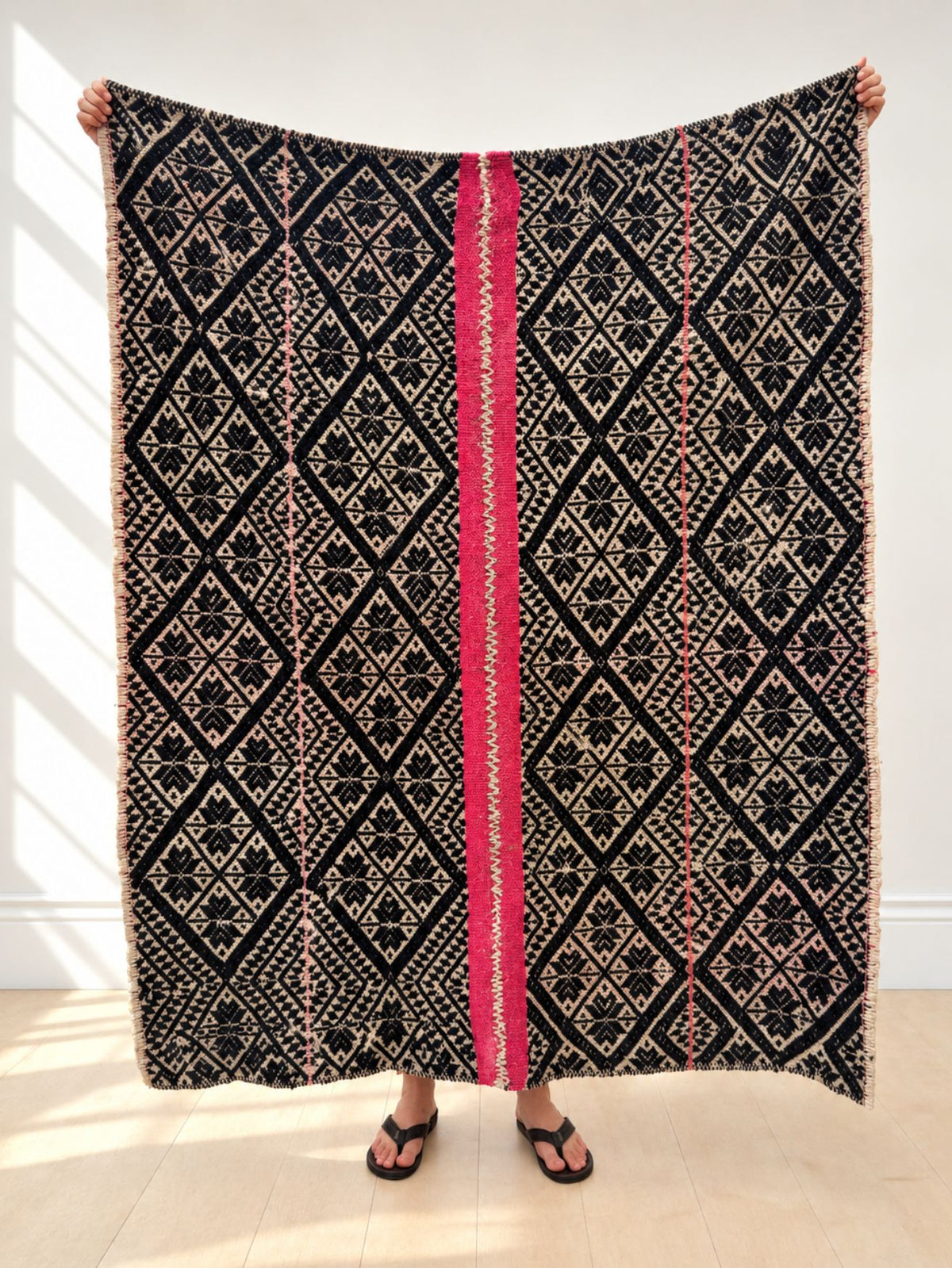 Vintage frazada rug No. 10 held up in full — black, cream and hot pink, handwoven Peruvian sheep and alpaca wool, 174 × 132 cm | Orange Inca