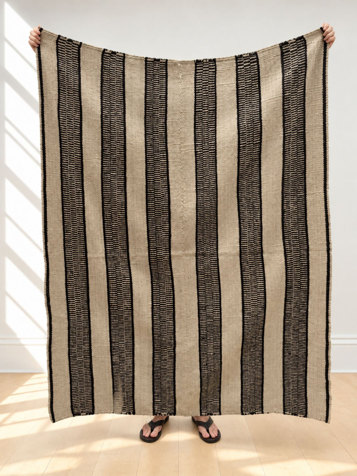Vintage frazada rug No. 21 held up in full — oatmeal and black, handwoven Peruvian sheep and alpaca wool, 182 × 134 cm | Orange Inca