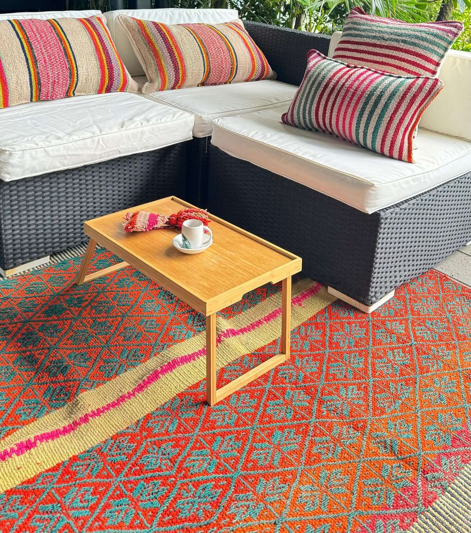 Peruvian frazada wool throw no 16 styled as outdoor rug showing bohemian pattern in washed orange, yellow and green