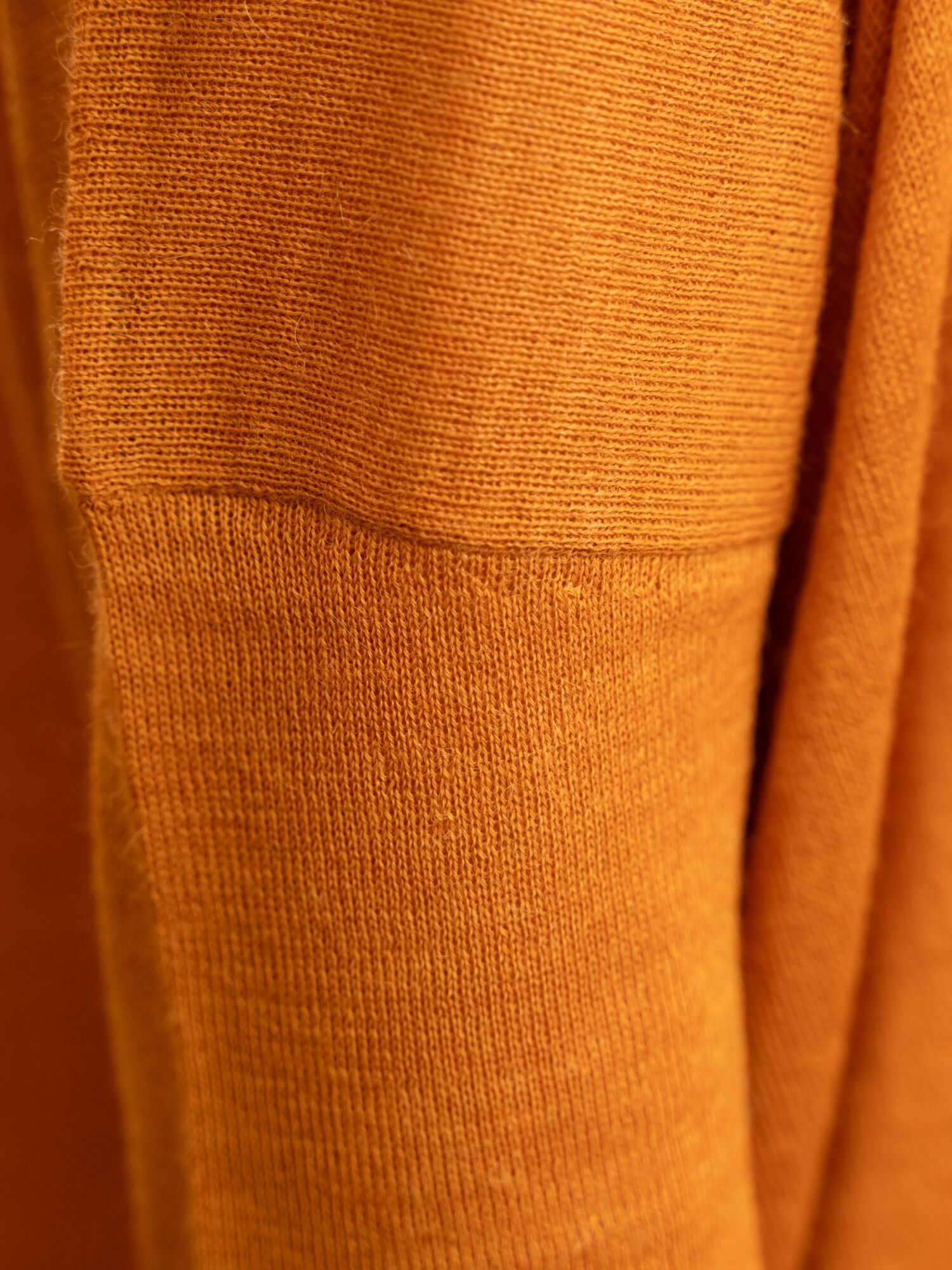 Folded view of turmeric jumper showcasing baby alpaca wool texture and tone