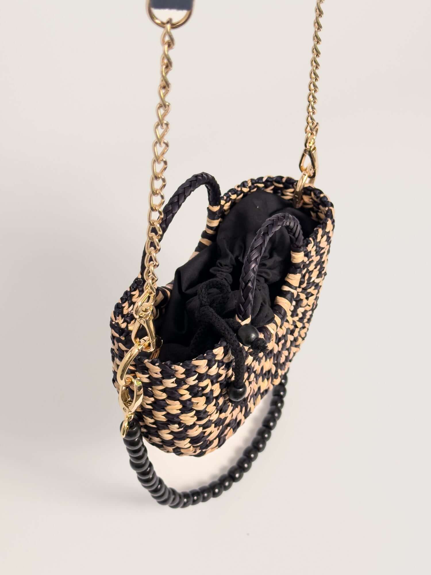 The Fiesta Mini Deluxe - Checkered Black and Natural handwoven junco crossbody bag with chain strap and wooden beads.