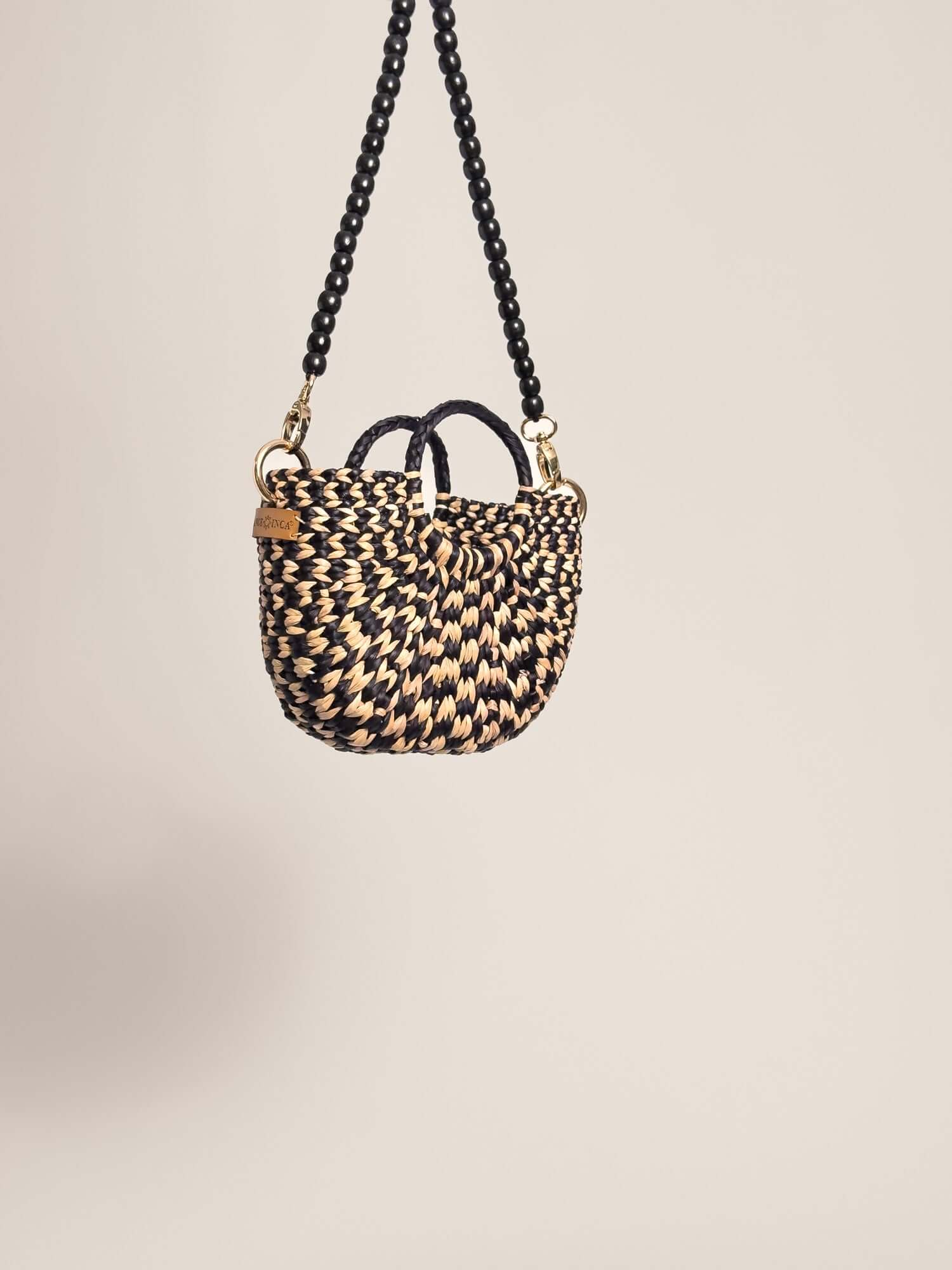 The Fiesta Mini Deluxe - Checkered Black and Natural handwoven junco crossbody bag with black bead strap and handles.