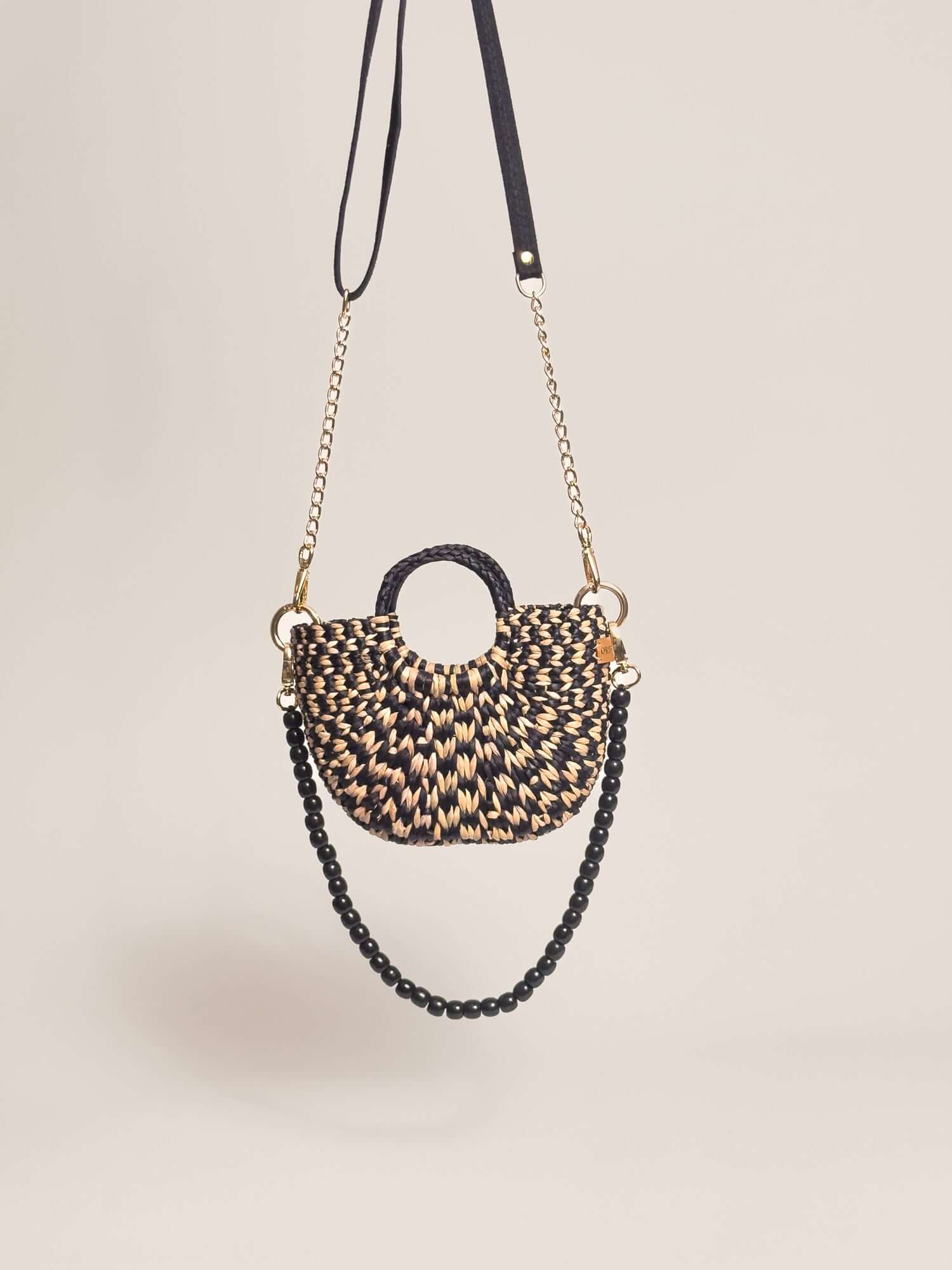 The Fiesta Mini Deluxe - Checkered Black and Natural handwoven junco crossbody bag with chain and wooden bead straps.