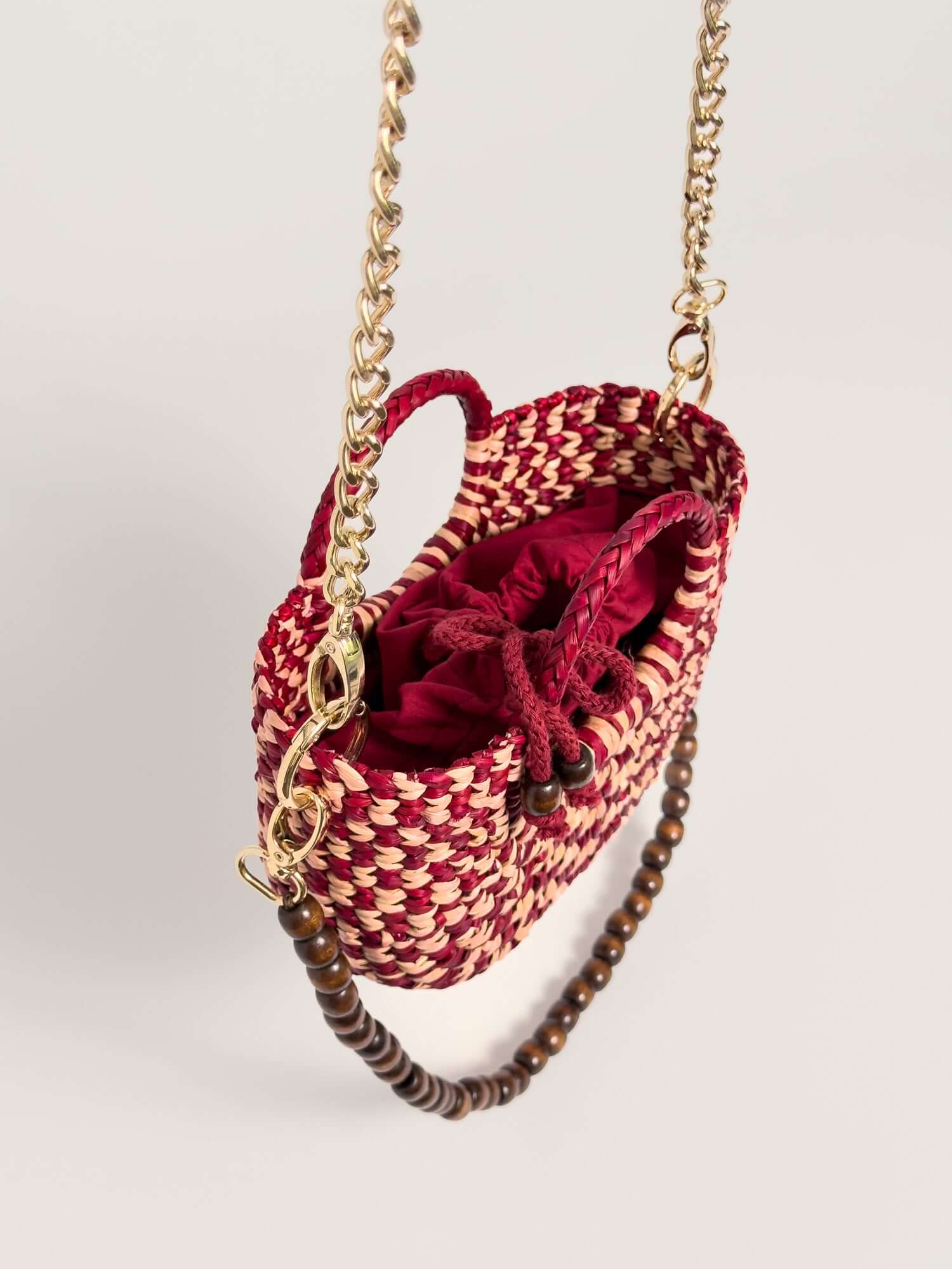 Alt Tag: The Fiesta Mini Deluxe - Checkered Burgundy and Natural handwoven junco crossbody bag with chain and wooden beads strap.