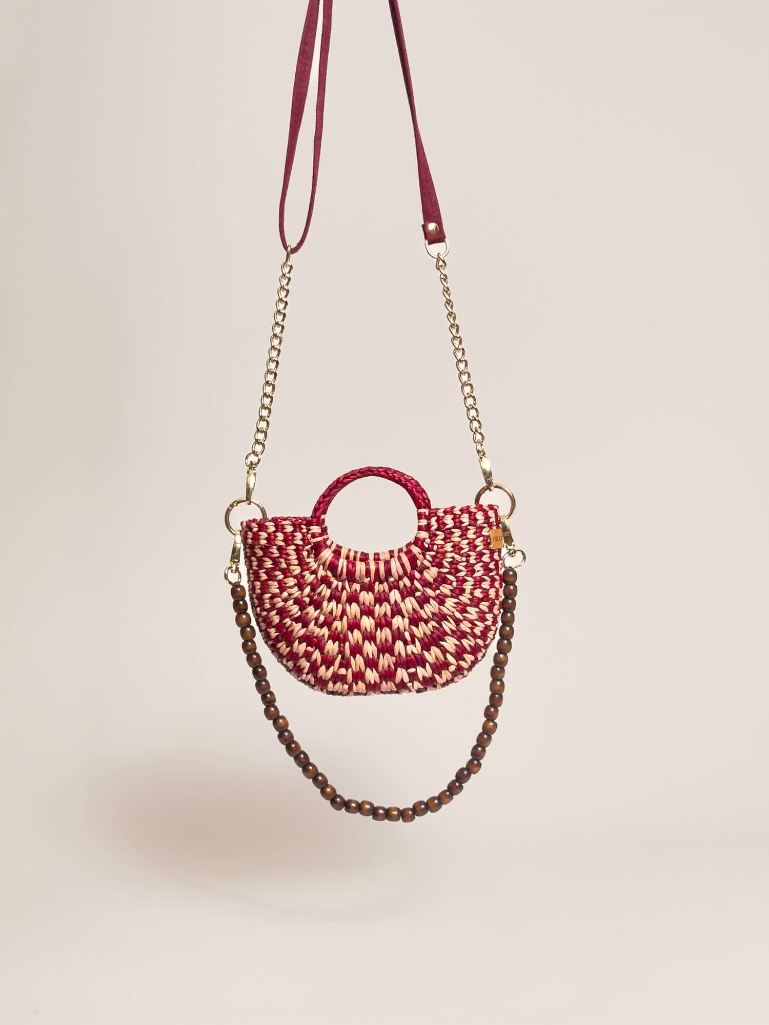 The Fiesta Mini Deluxe - Checkered Burgundy and Natural handwoven junco crossbody bag with a chain and wooden beads strap.