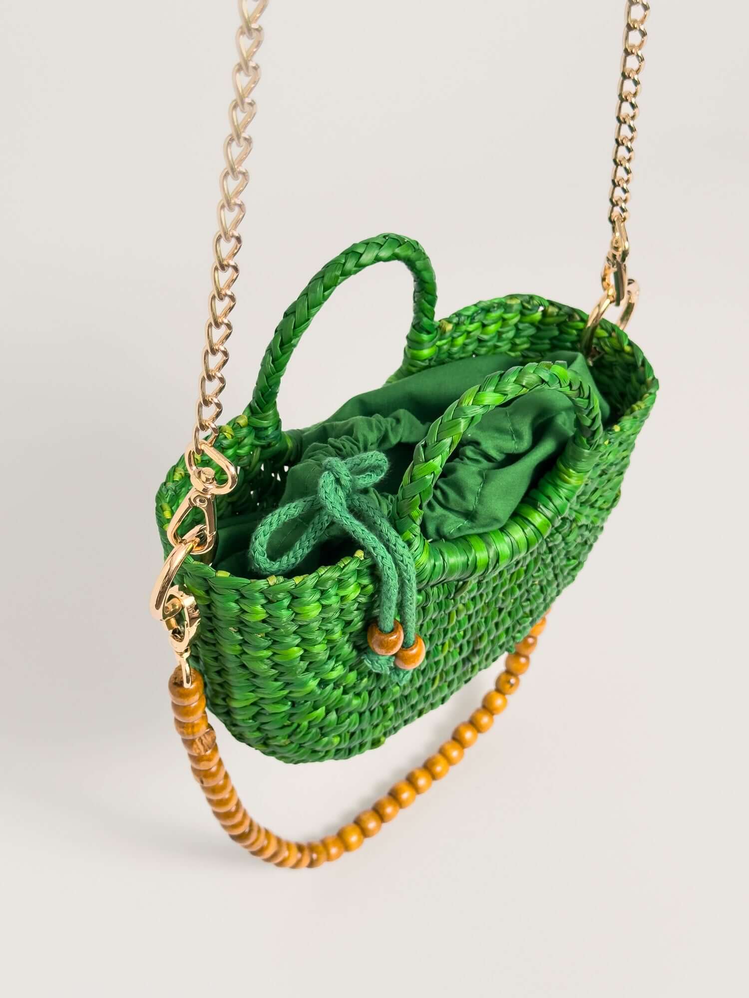 The Fiesta Mini Deluxe - Emerald Green, handwoven junco crossbody bag, featuring green woven material, chain and wooden beads strap.