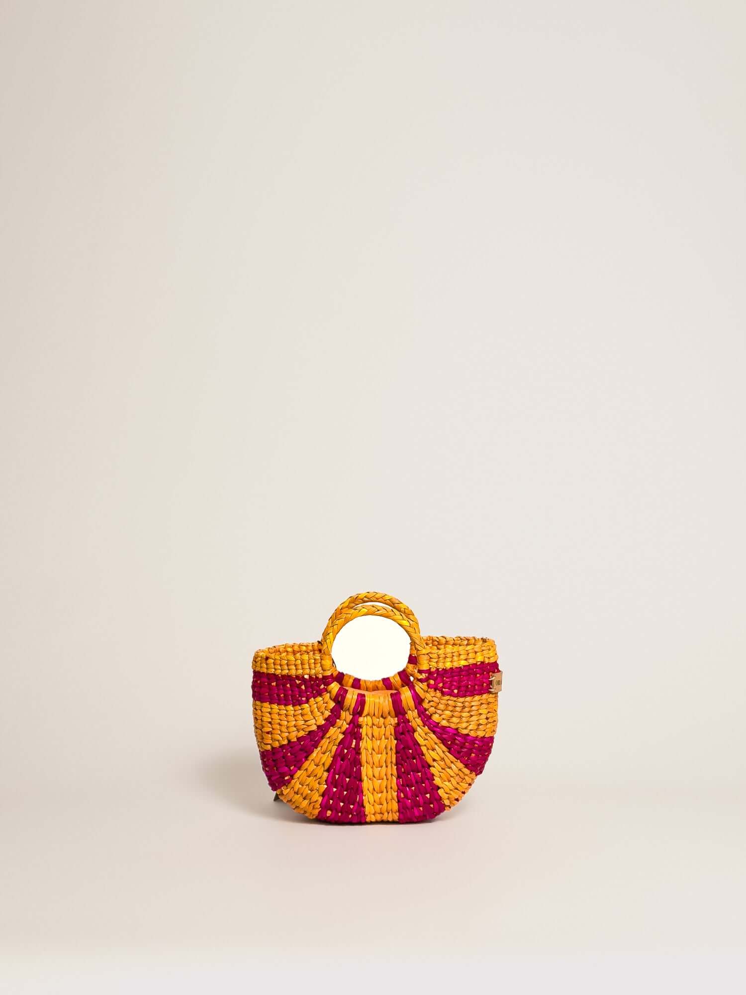 The Fiesta Mini Deluxe - Striped Fuchsia and Orange, handwoven junco crossbody bag, featuring natural fibres, with a rounded handle.