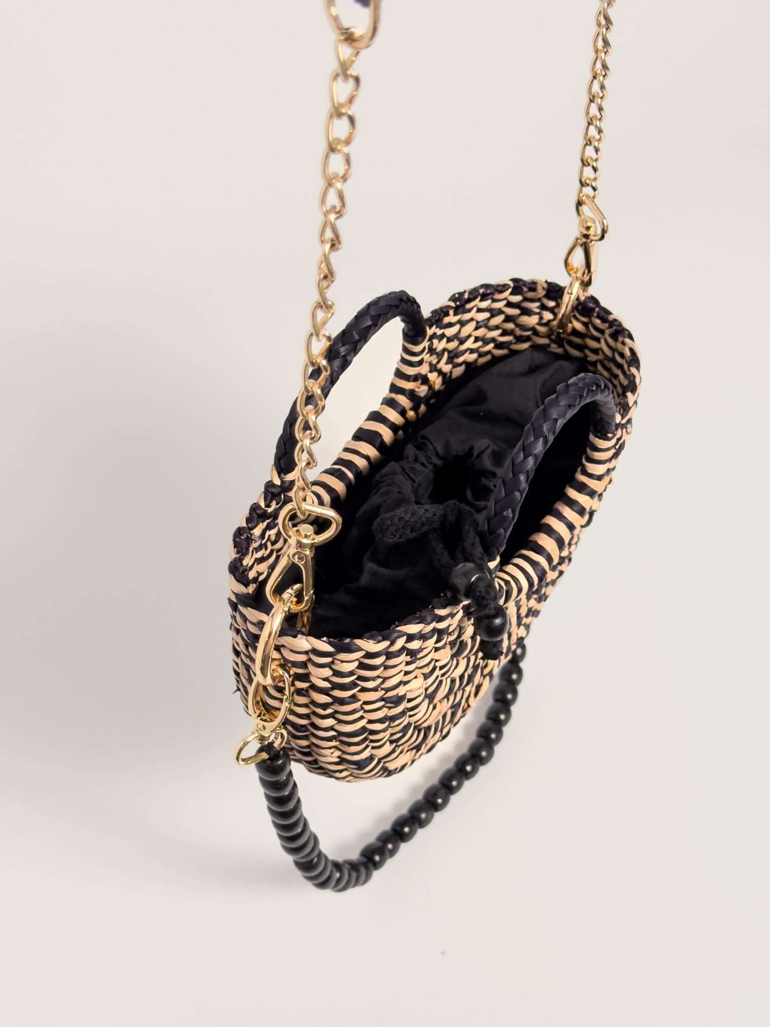 The Fiesta Mini Deluxe - Marbled Black and Natural handwoven junco crossbody bag with chain strap and wooden bead features.