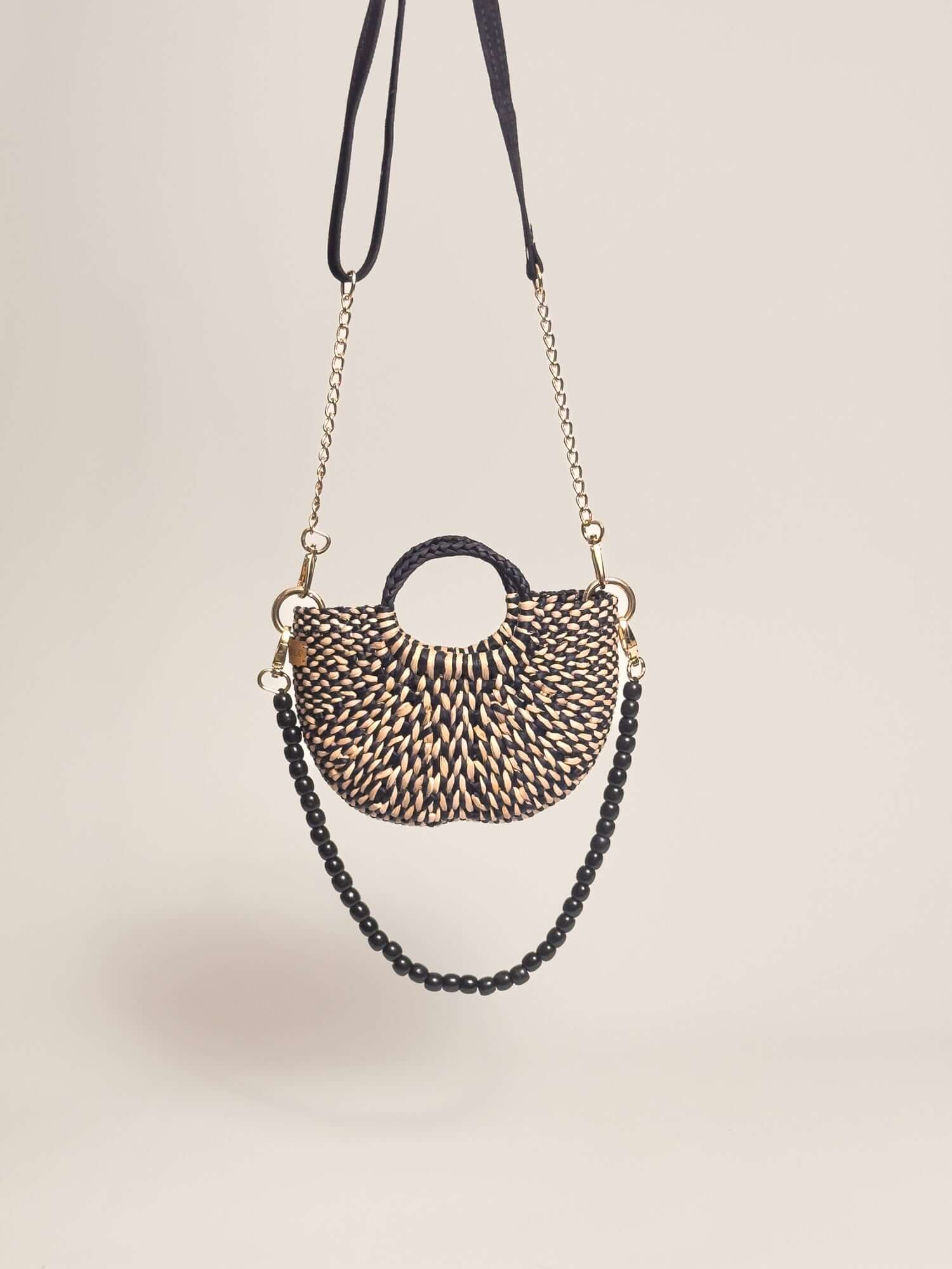 The Fiesta Mini Deluxe - Marbled Black and Natural handwoven junco crossbody bag with chain and wooden bead strap.