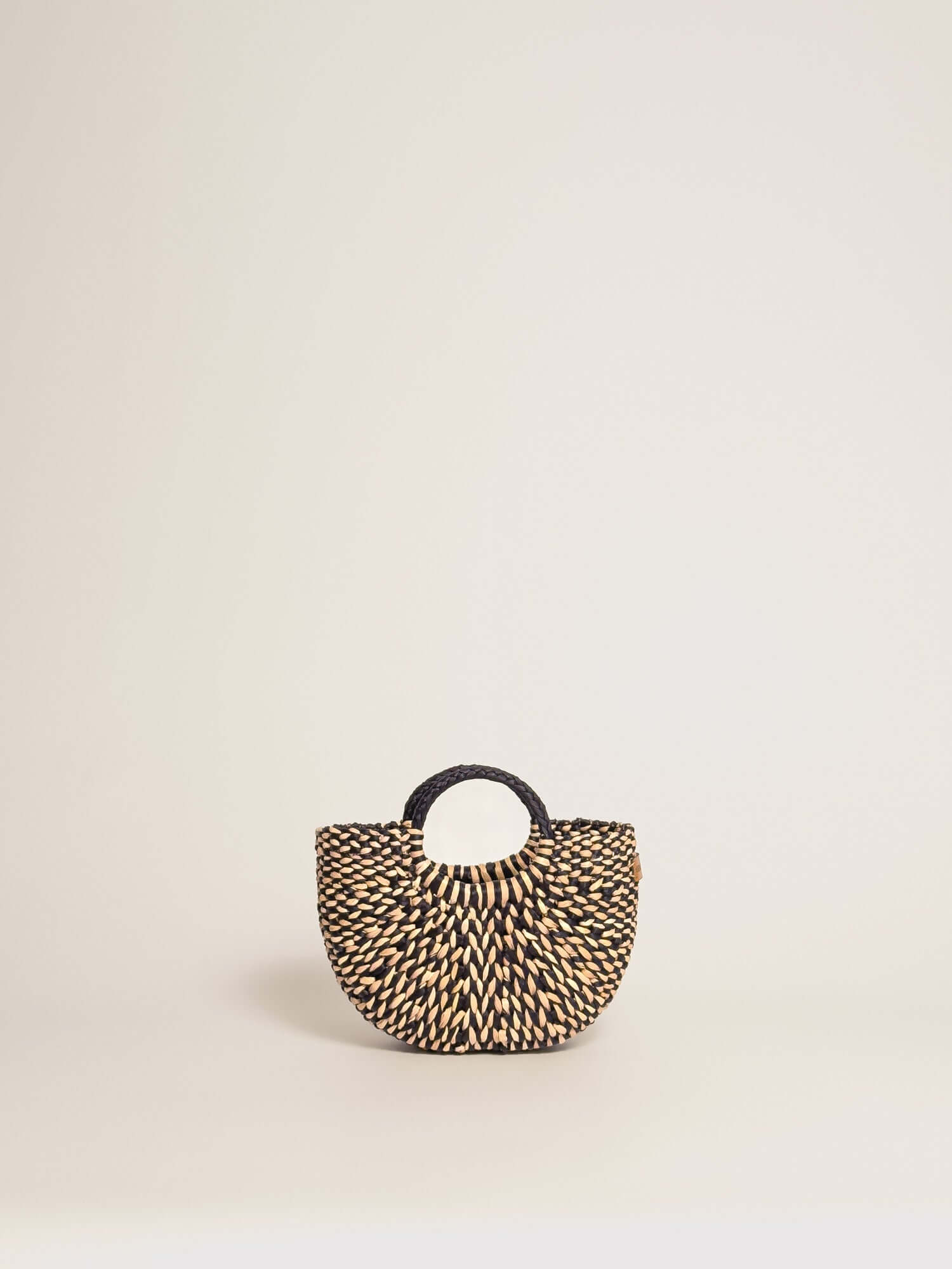 The Fiesta Mini Deluxe - Marbled Black and Natural handwoven junco crossbody bag with a round handle.