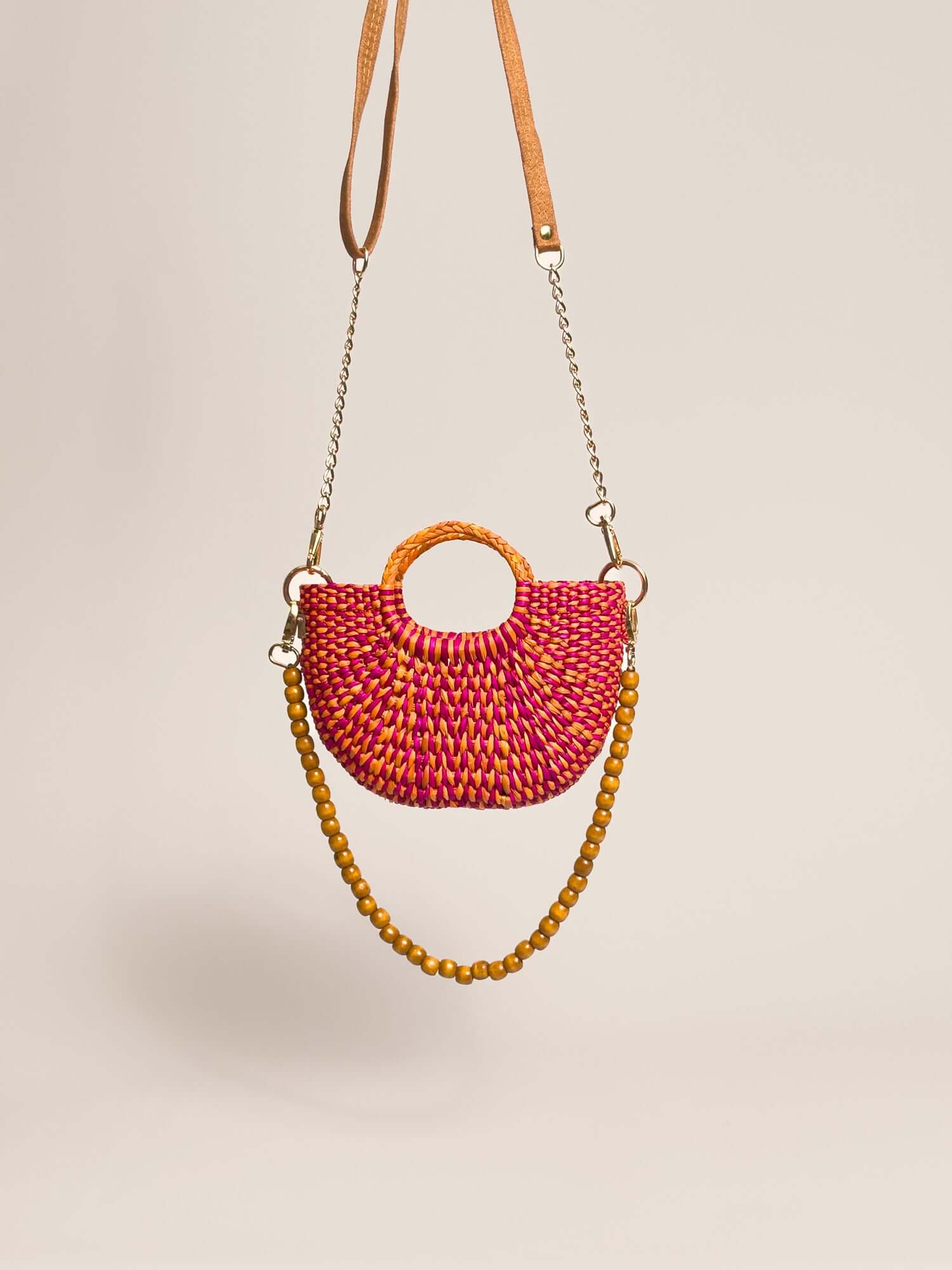 The Fiesta Mini Deluxe - Marbled Fuchsia and Orange handwoven junco crossbody bag with chain and wooden bead strap.