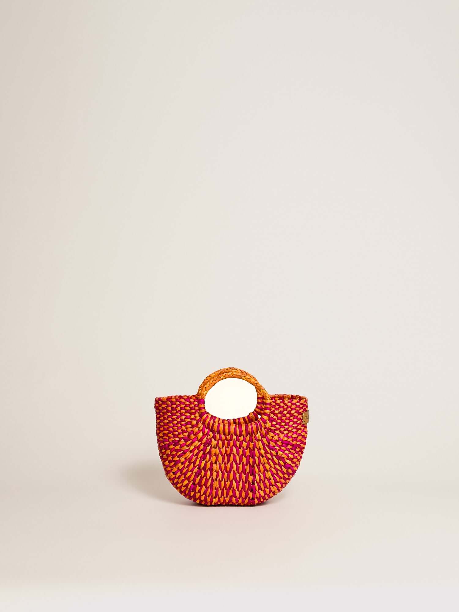 The Fiesta Mini Deluxe - Marbled Fuchsia and Orange handwoven junco crossbody bag with an orange handle and colorful woven design.