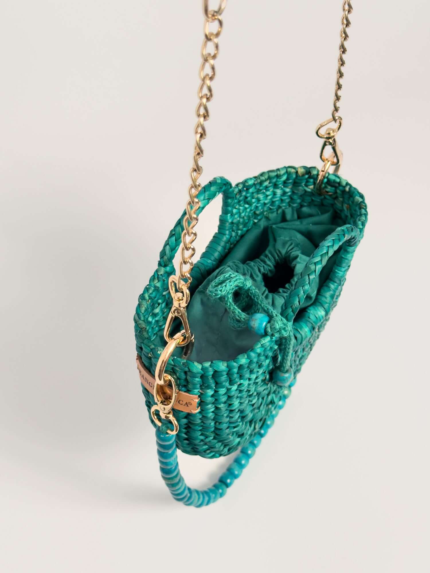 The Fiesta Mini Deluxe - Turquoise handwoven junco crossbody bag with chain strap and drawstring closure.