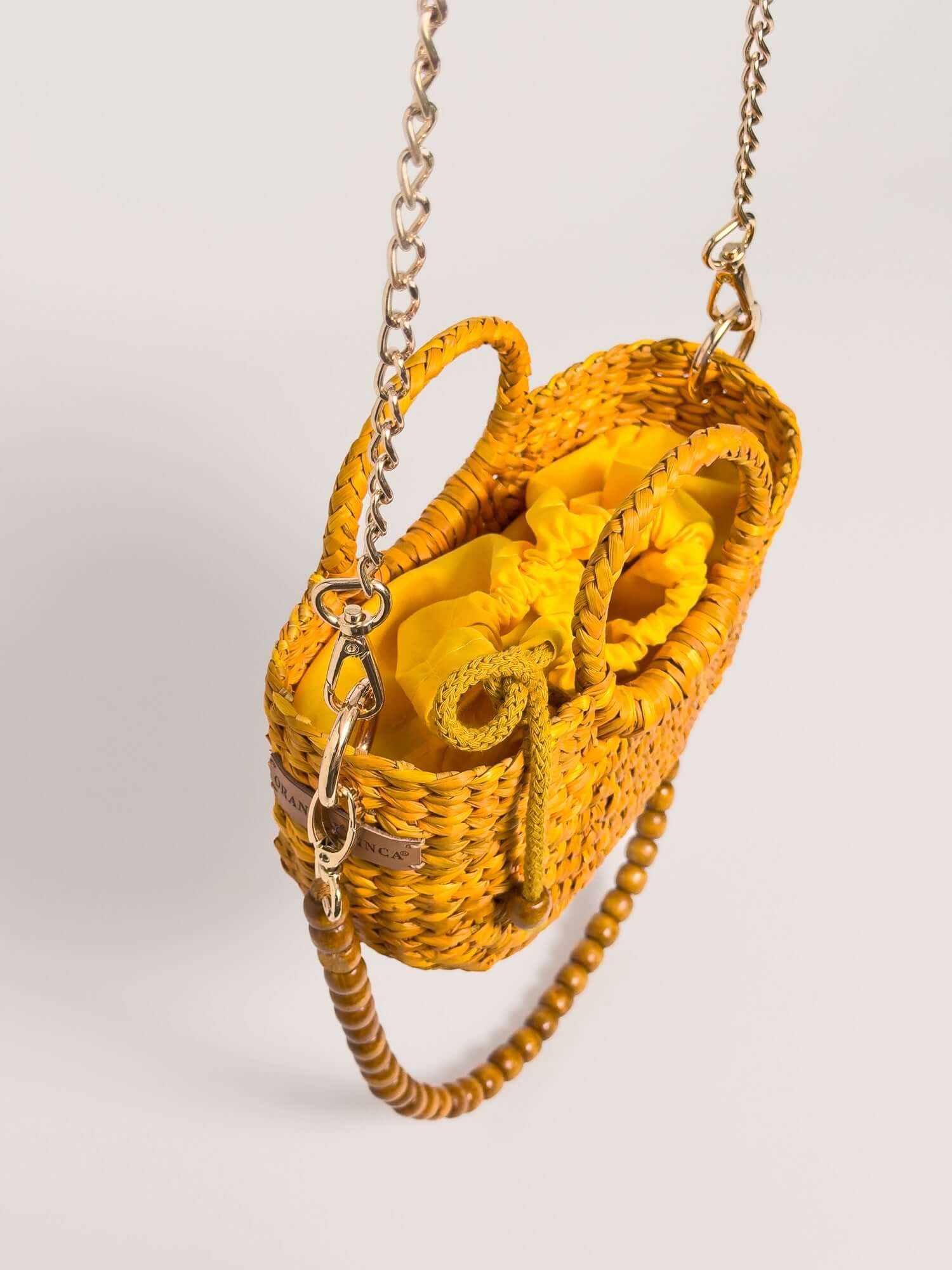 The Fiesta Mini Deluxe - Yellow handwoven junco crossbody bag with yellow fabric interior and chain strap.