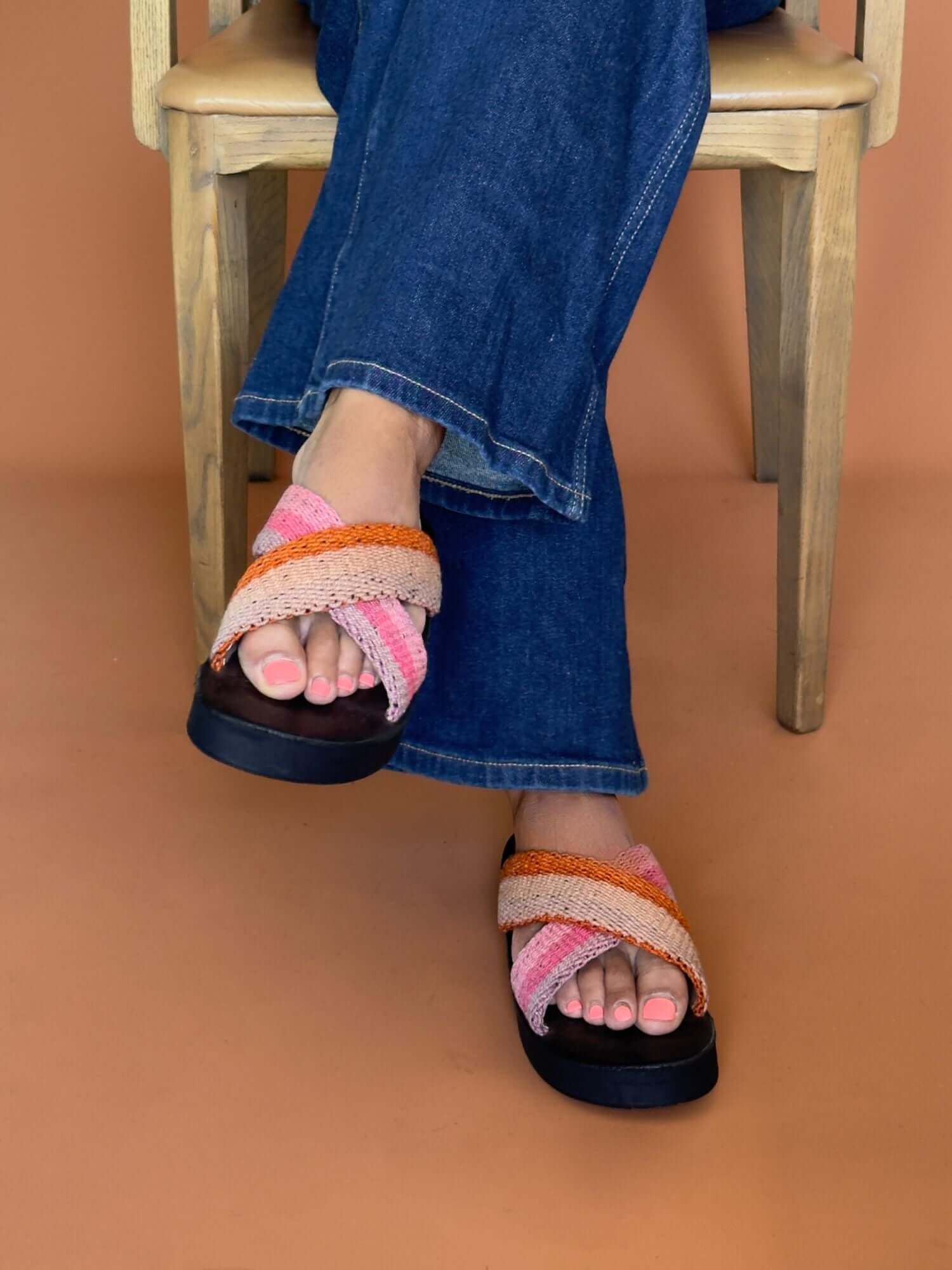 Pink and orange leatherx sandals with handwoven wool straps, lifestyle shot.