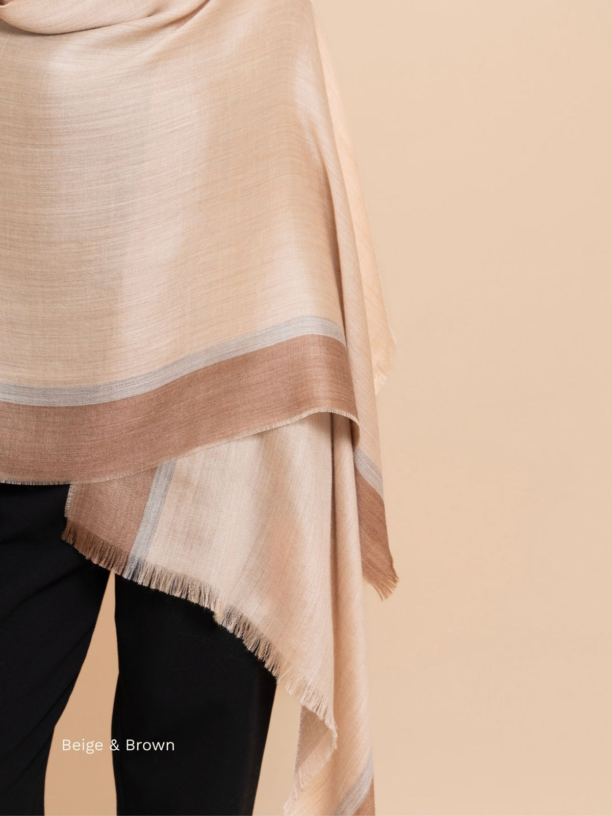 Beige and camel silk baby alpaca blend shawl draped over the shoulders, brown border and soft fringe