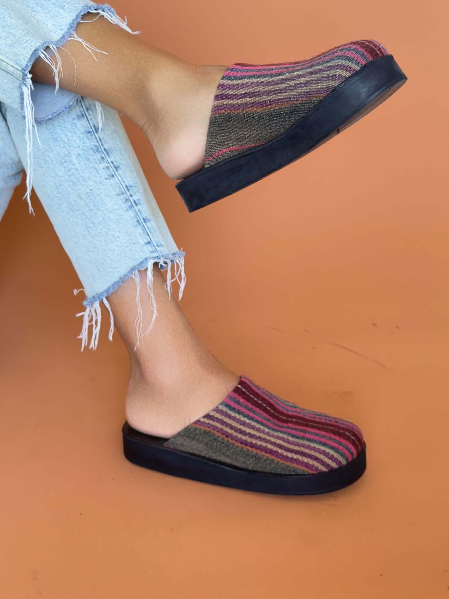 Sustainable leather clogs with vibrant wool stripes, lifestyle shot.