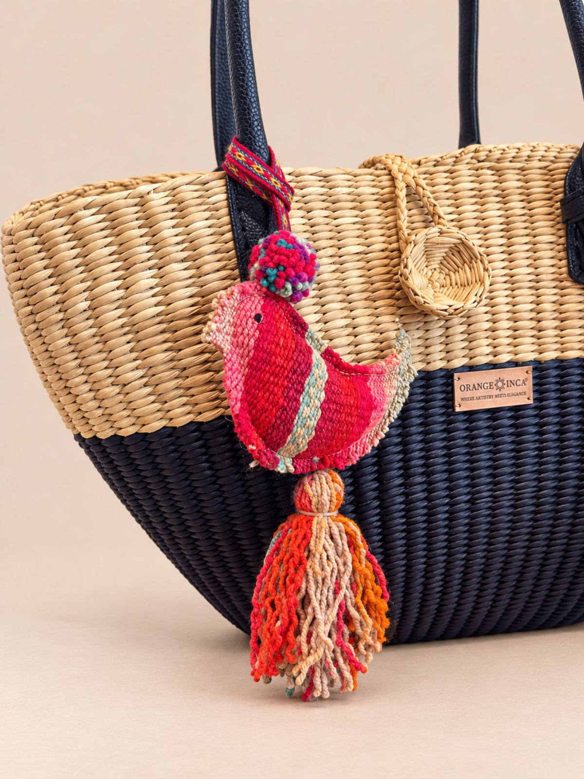 Bird wool tassel hanging as a bag charm on a navy and natural woven basket bag | Tasselita by Orange Inca