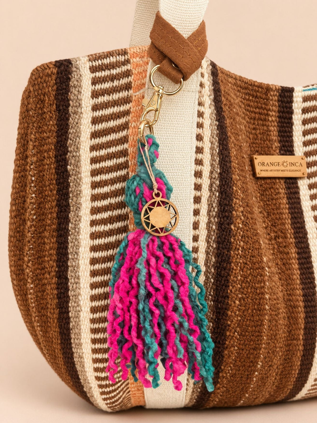 Fuchsia and green wool tassel with faux suede wrist strap attached to a bag