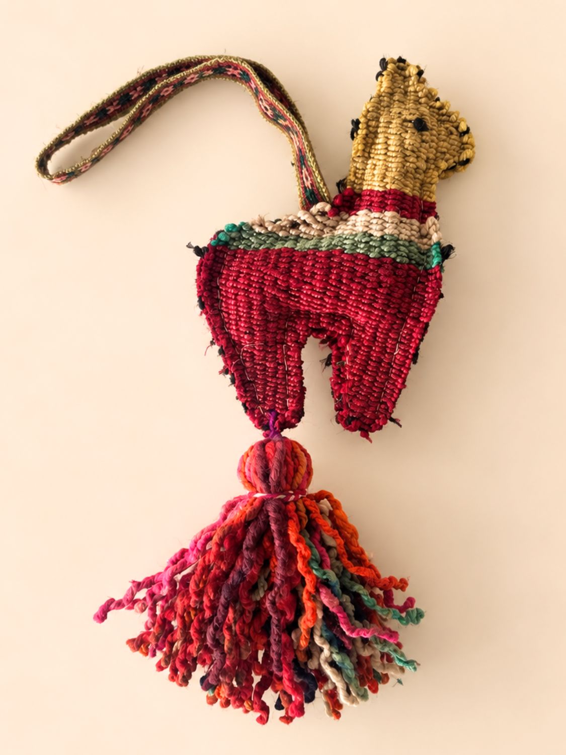 Large llama wool tassel with a crimson body, striped back and mustard head, hanging from a multicolour tassel – handmade in Peru | Tasselita by Orange Inca