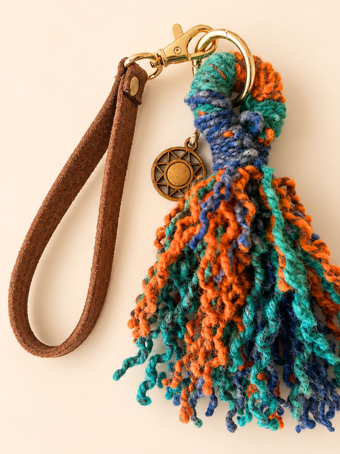 Washed blue and orange wool tassel with a faux suede wrist strap and light gold hardware