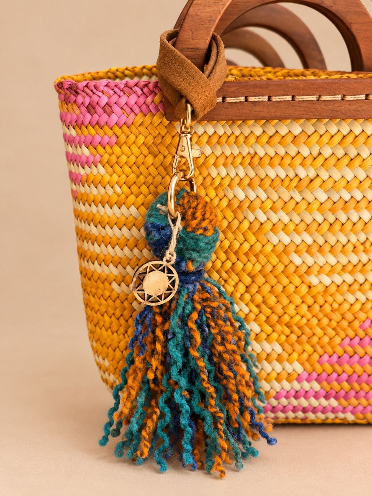 Washed blue and orange wool tassel with faux suede wrist strap attached to a bag
