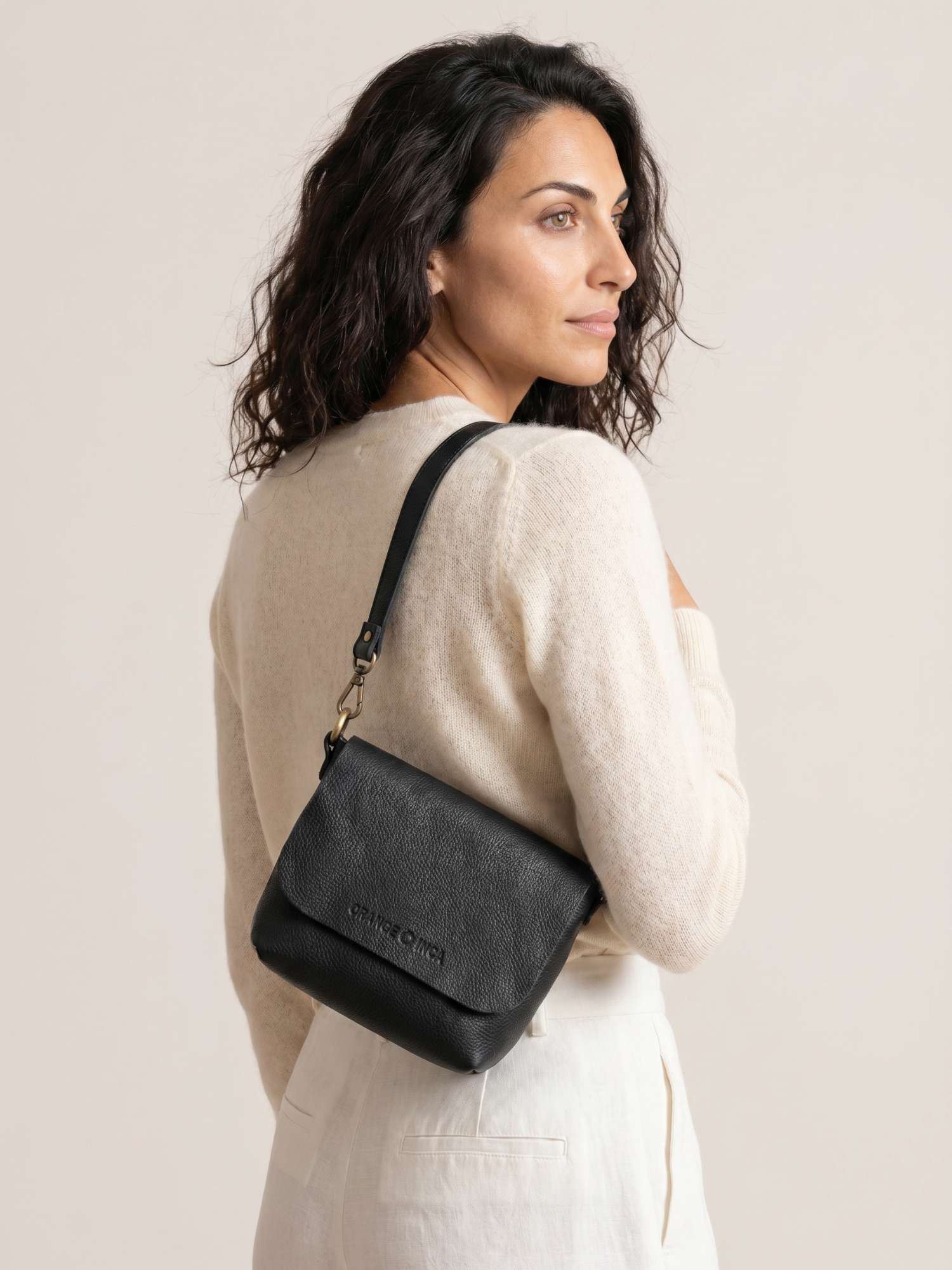 The Olivia Black leather crossbody bag worn over the shoulder with the short strap — full-grain leather | Orange Inca