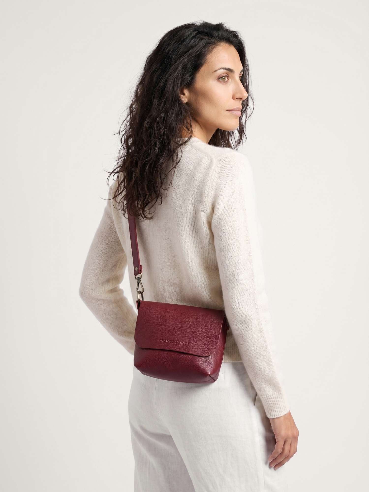 The Olivia Burgundy leather crossbody bag worn across the body — adjustable long strap, hands-free carry | Orange Inca