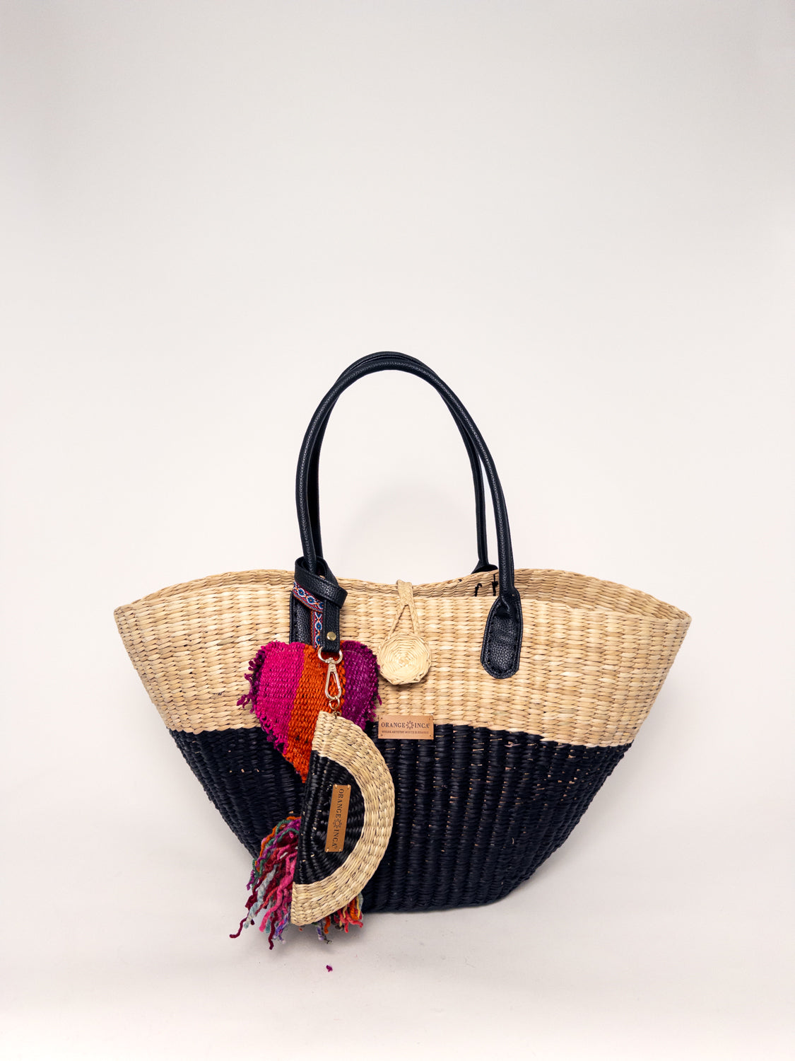 Playa Tote - Half Natural Half Black, handwoven junco tote bag with faux leather straps, natural dyes, and colorful tassel.