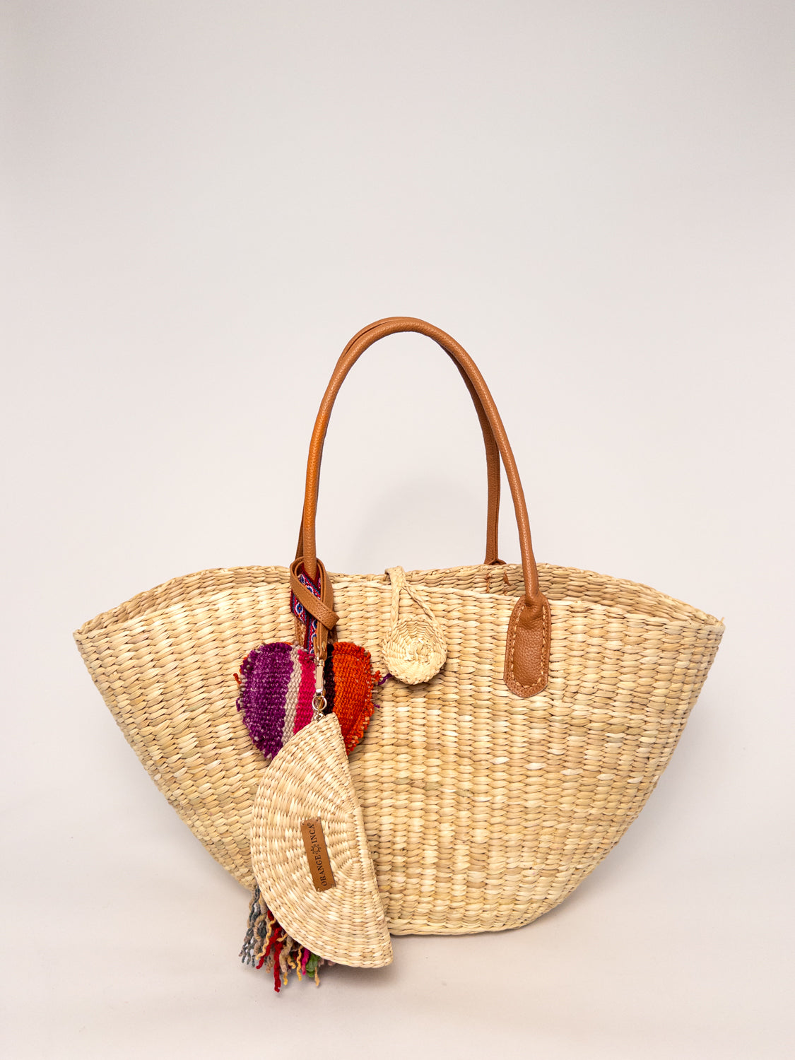 Playa Tote - Natural, handwoven junco tote bag, structured shape, faux leather straps, natural dyes, and decorative tassel.