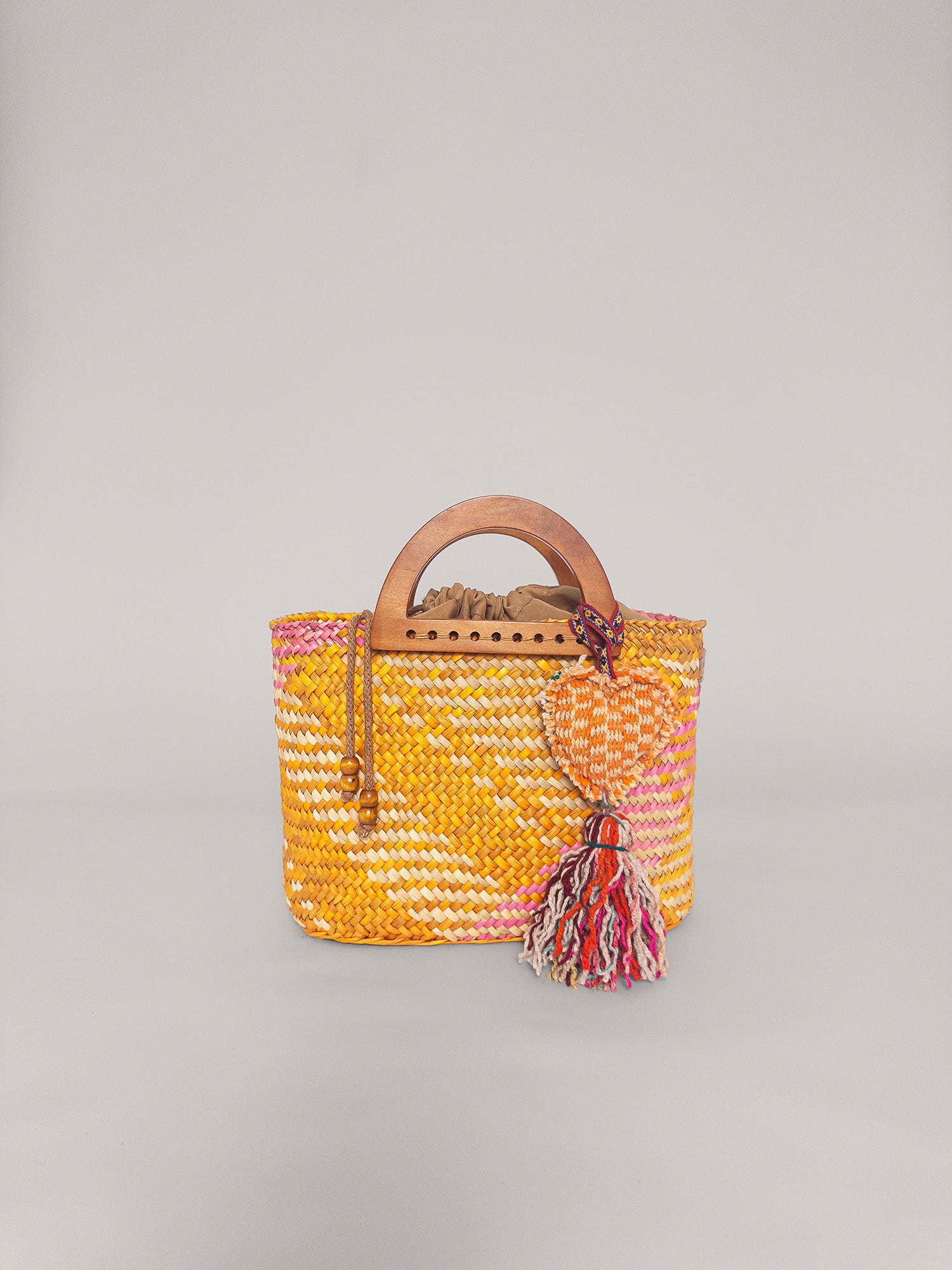 The Sophia bag in washed yellow and pink, handwoven with wooden handles and a colorful tassel.