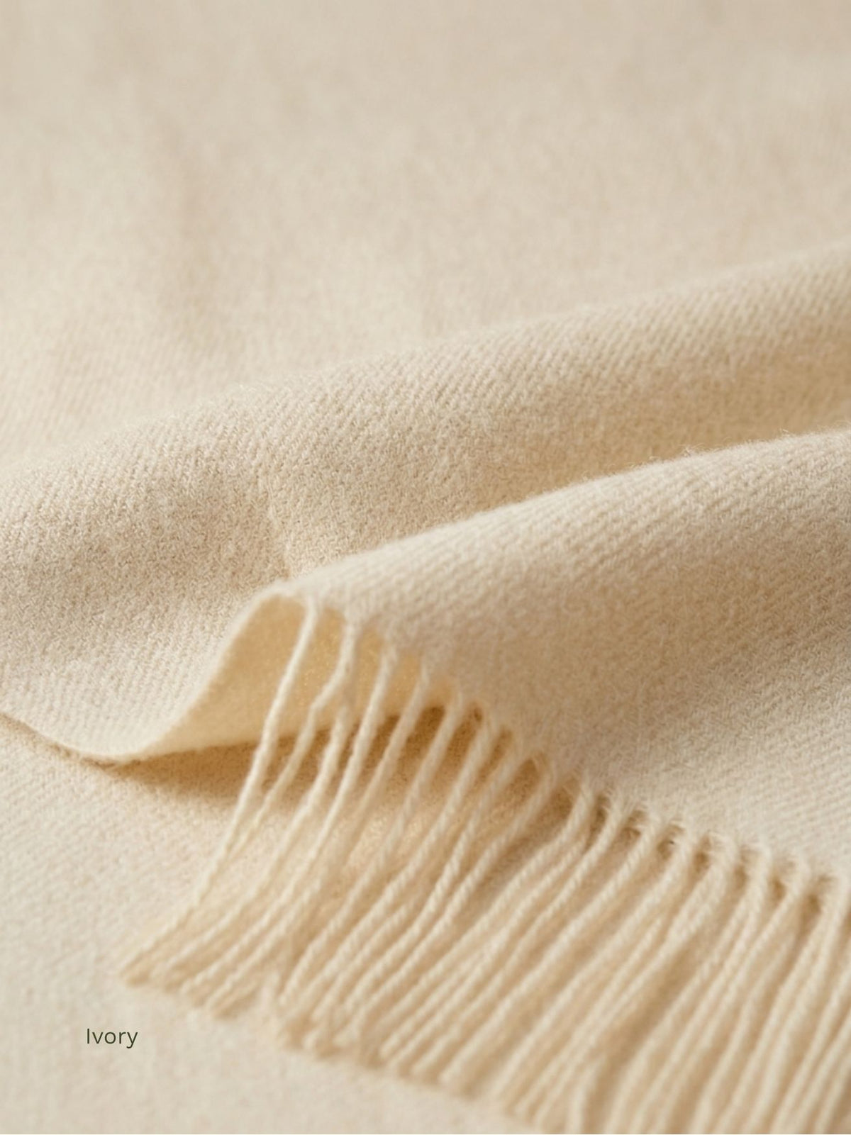Folded corner of an ivory baby alpaca shawl, close-up of the soft brushed fibre and fringe, softer than cashmere