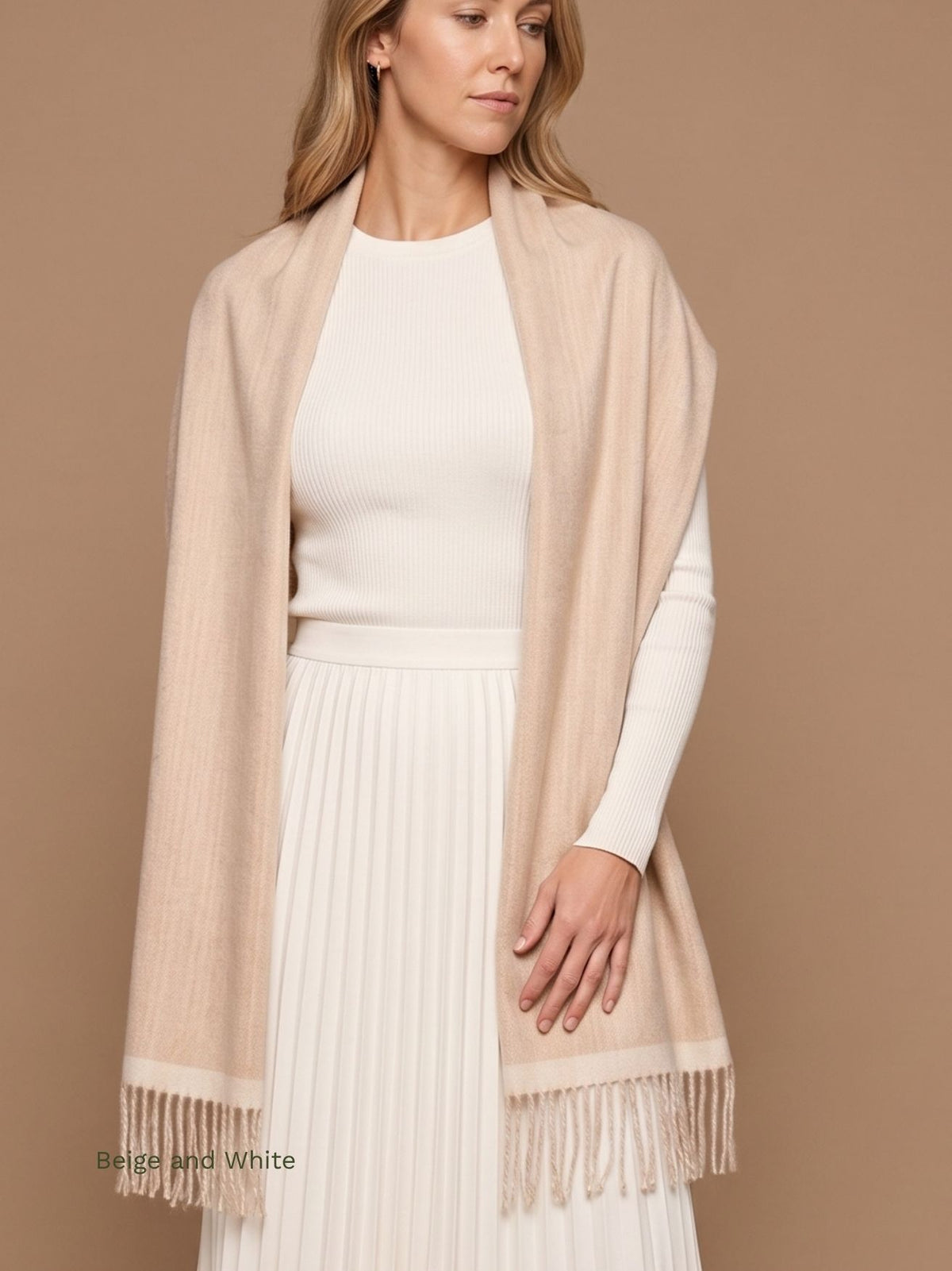 Woman wearing a beige and white double face baby alpaca scarf draped as a wrap over a white top and pleated skirt. Orange Inca