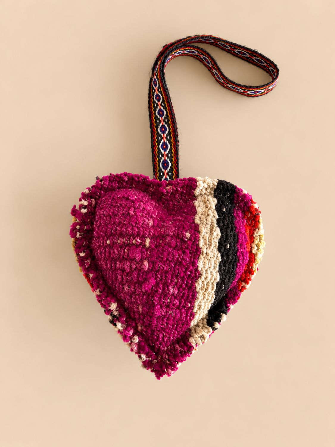 Large magenta heart wool charm with black, cream and red stripes on a woven loop | Tasselita by Orange Inca