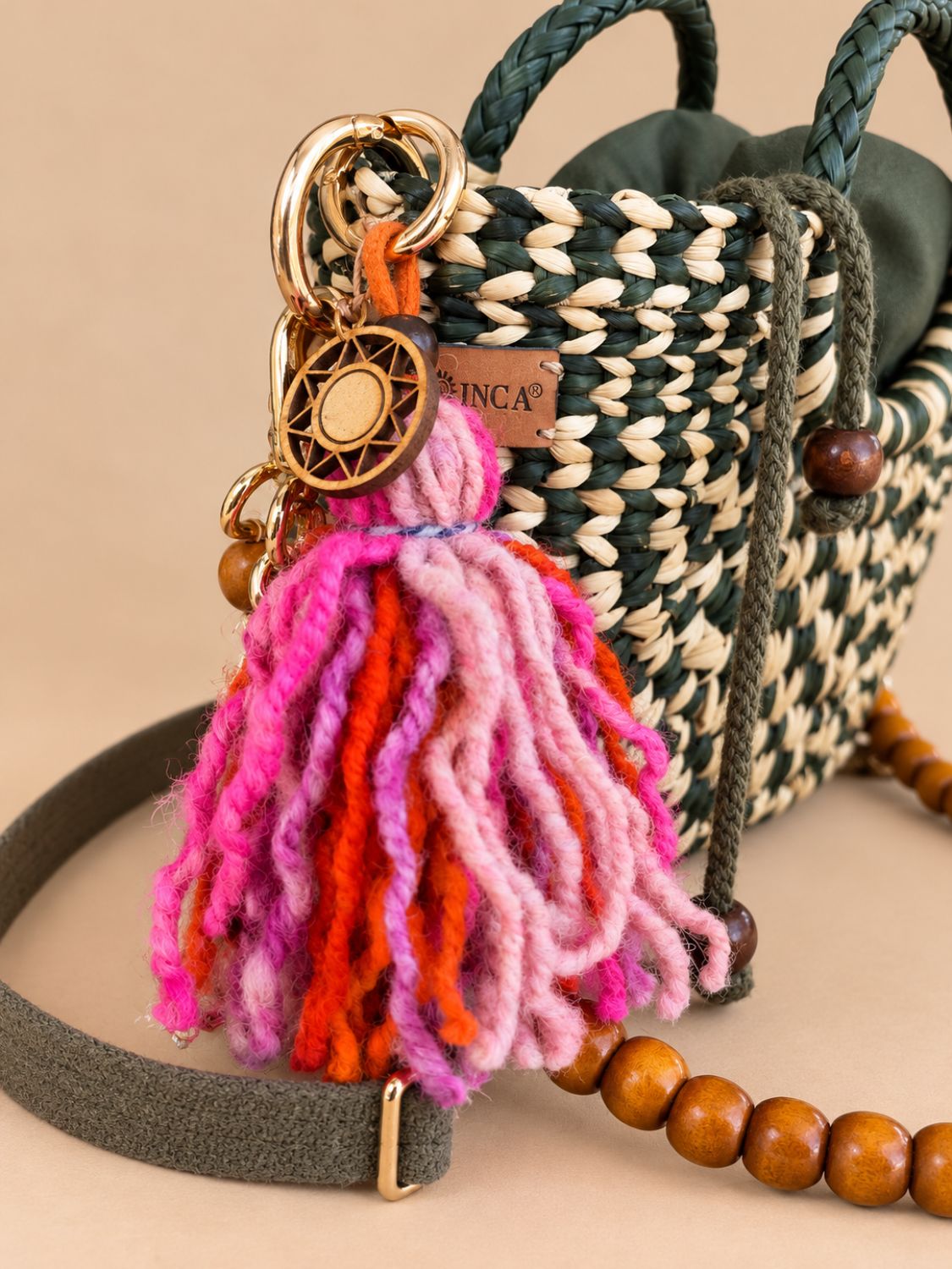 Chunky wool charm attached to a dark green straw bag | Tasselita by Orange Inca