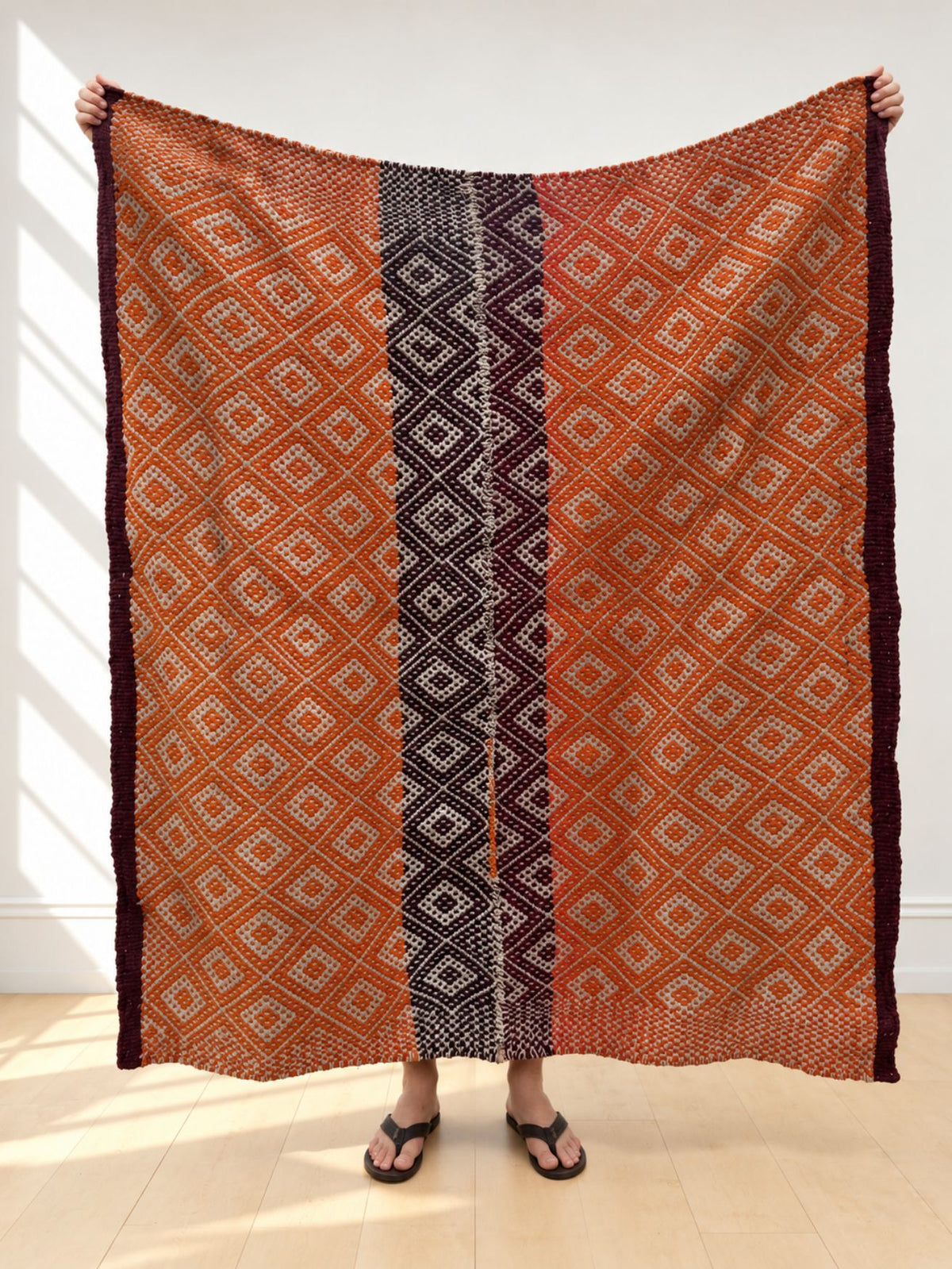 Vintage frazada rug No. 11 held up in full — burnt orange, cream and aubergine, handwoven Peruvian sheep and alpaca wool, 177 × 150 cm | Orange Inca