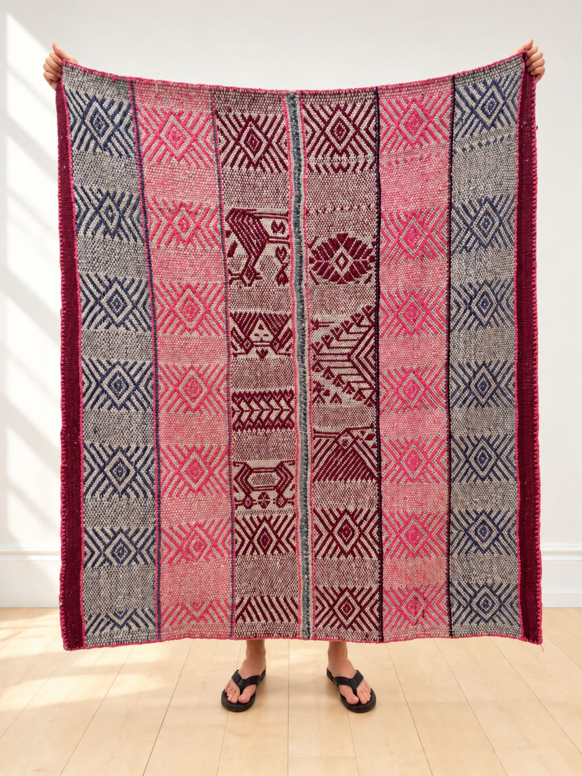 Vintage frazada rug No. 13 held up in full — pink and slate-blue diamond bands with a central panel of burgundy birds, handwoven Peruvian sheep and alpaca wool, 156 × 141 cm | Orange Inca