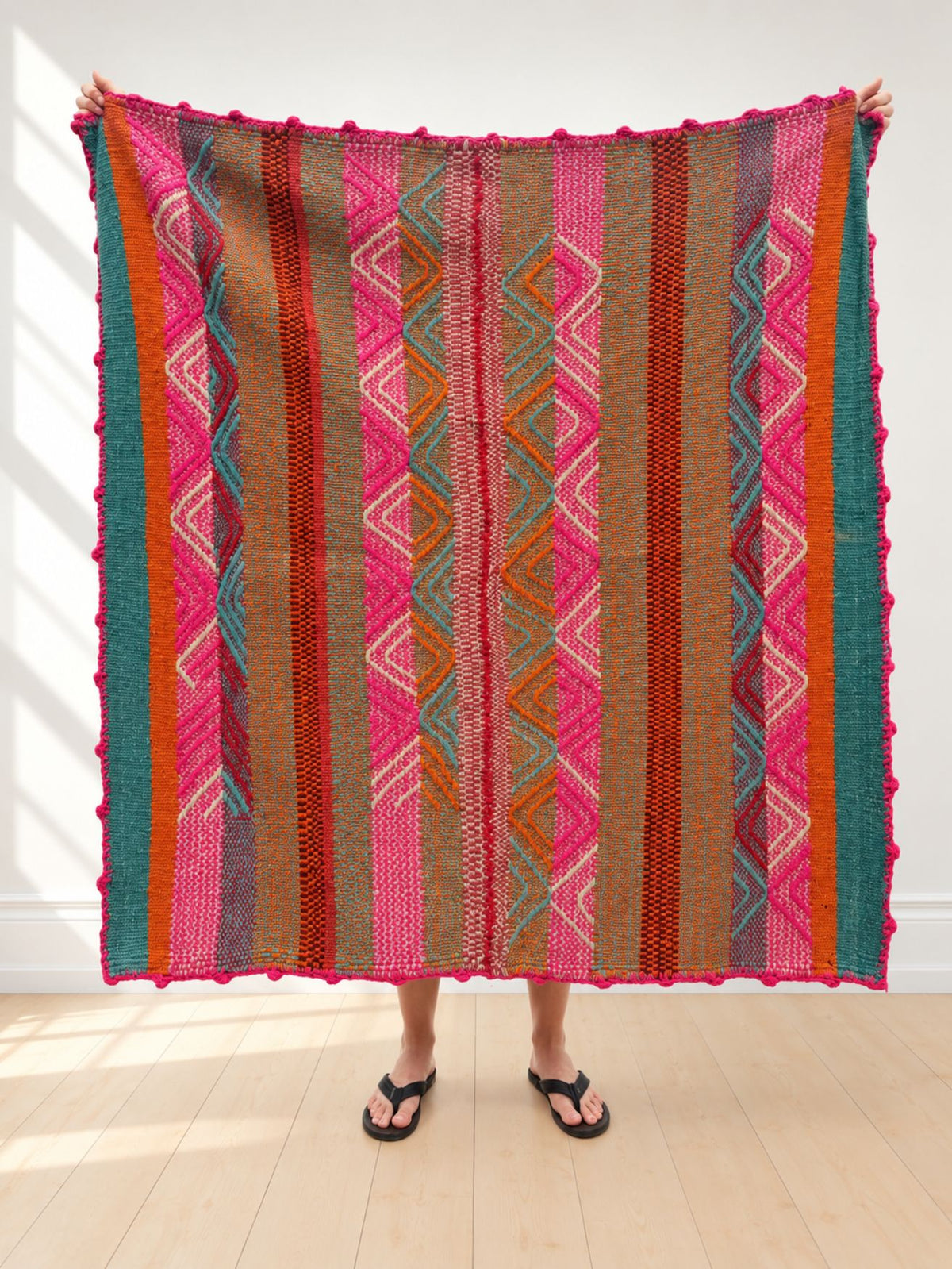 Vintage frazada rug No. 15 held up in full — hot pink, teal, burnt orange and caramel stripes with a crocheted bobble border, handwoven Peruvian sheep and alpaca wool, 168 × 163 cm | Orange Inca