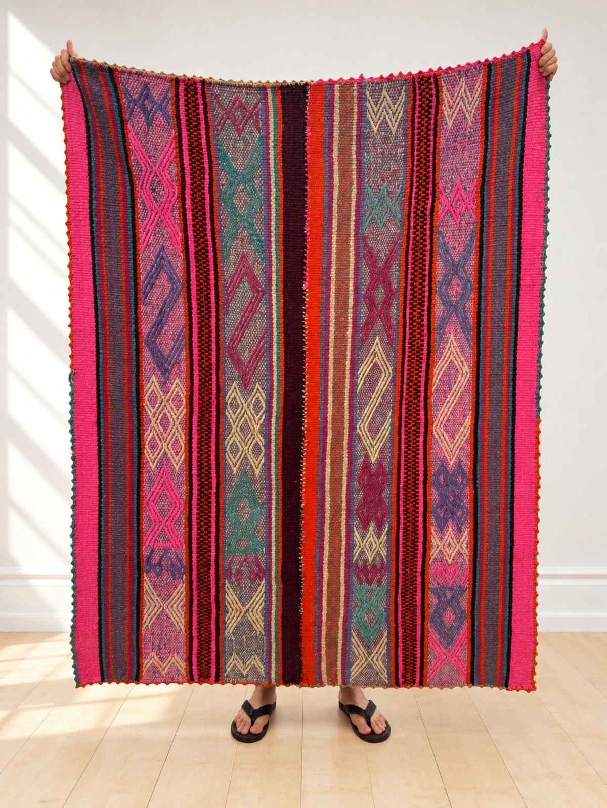 Vintage frazada rug No. 18 held up in full — hot pink, red, plum, teal and lilac diamond stripes, handwoven Peruvian sheep and alpaca wool, 172 × 132 cm | Orange Inca