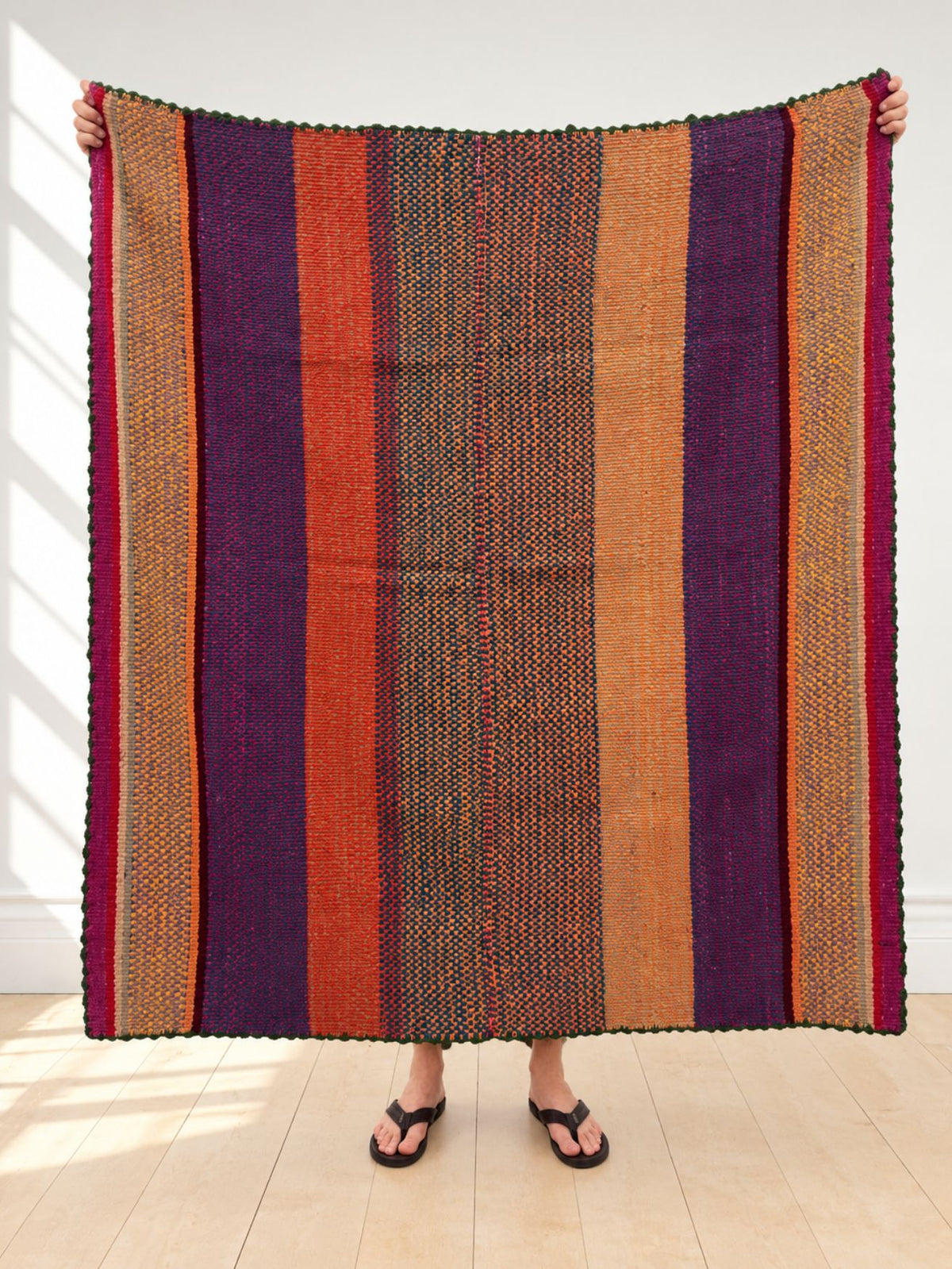 Vintage frazada rug No. 5 held up in full — deep purple, burnt orange, ochre and fuchsia stripes, handwoven Peruvian sheep and alpaca wool, 160 × 160 cm | Orange Inca