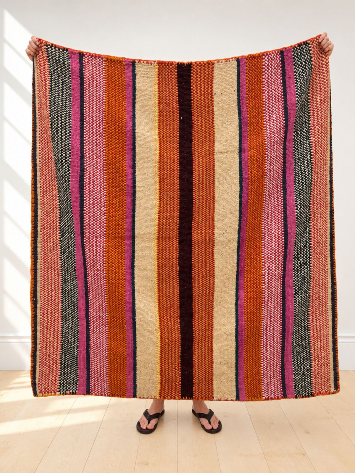 Vintage frazada rug No. 6 held up in full — burnt orange, cream, pink and black stripes, handwoven Peruvian sheep and alpaca wool, 173 × 171 cm | Orange Inca
