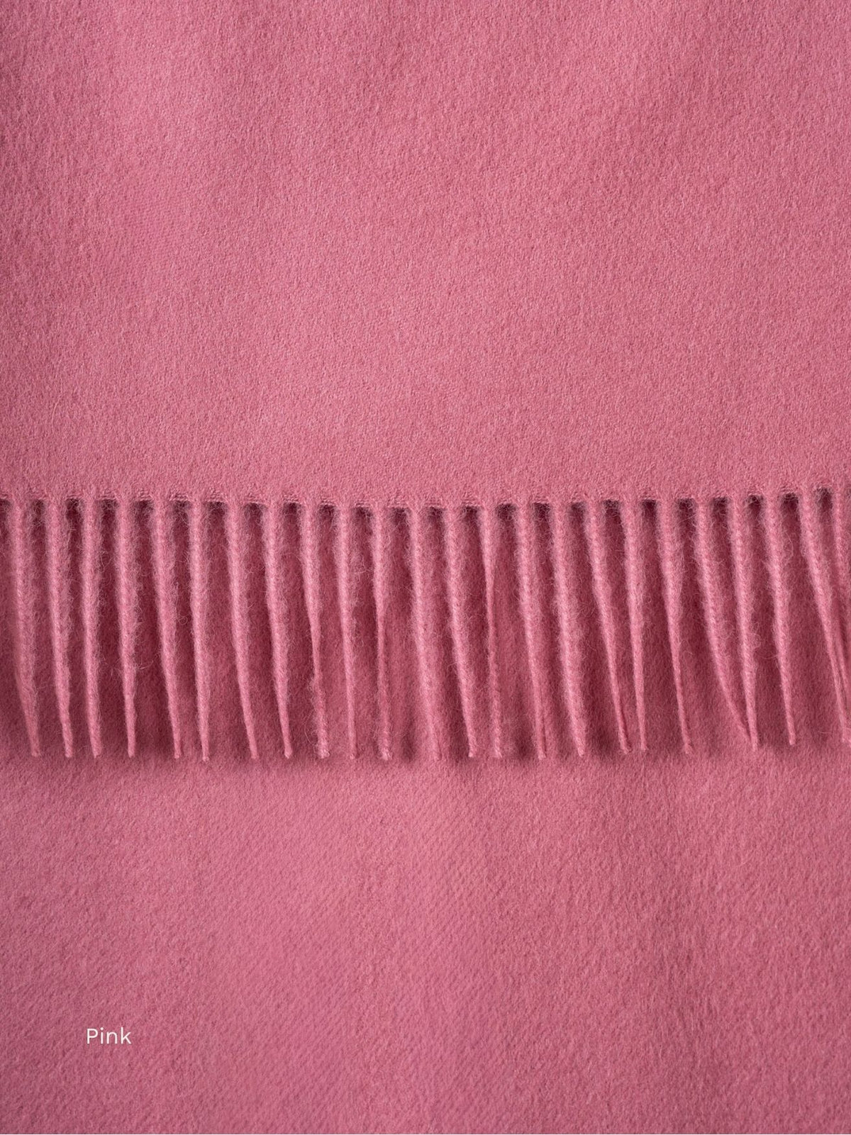 Pink naturally dyed baby alpaca scarf, close-up of the dusty rose fabric and fringe